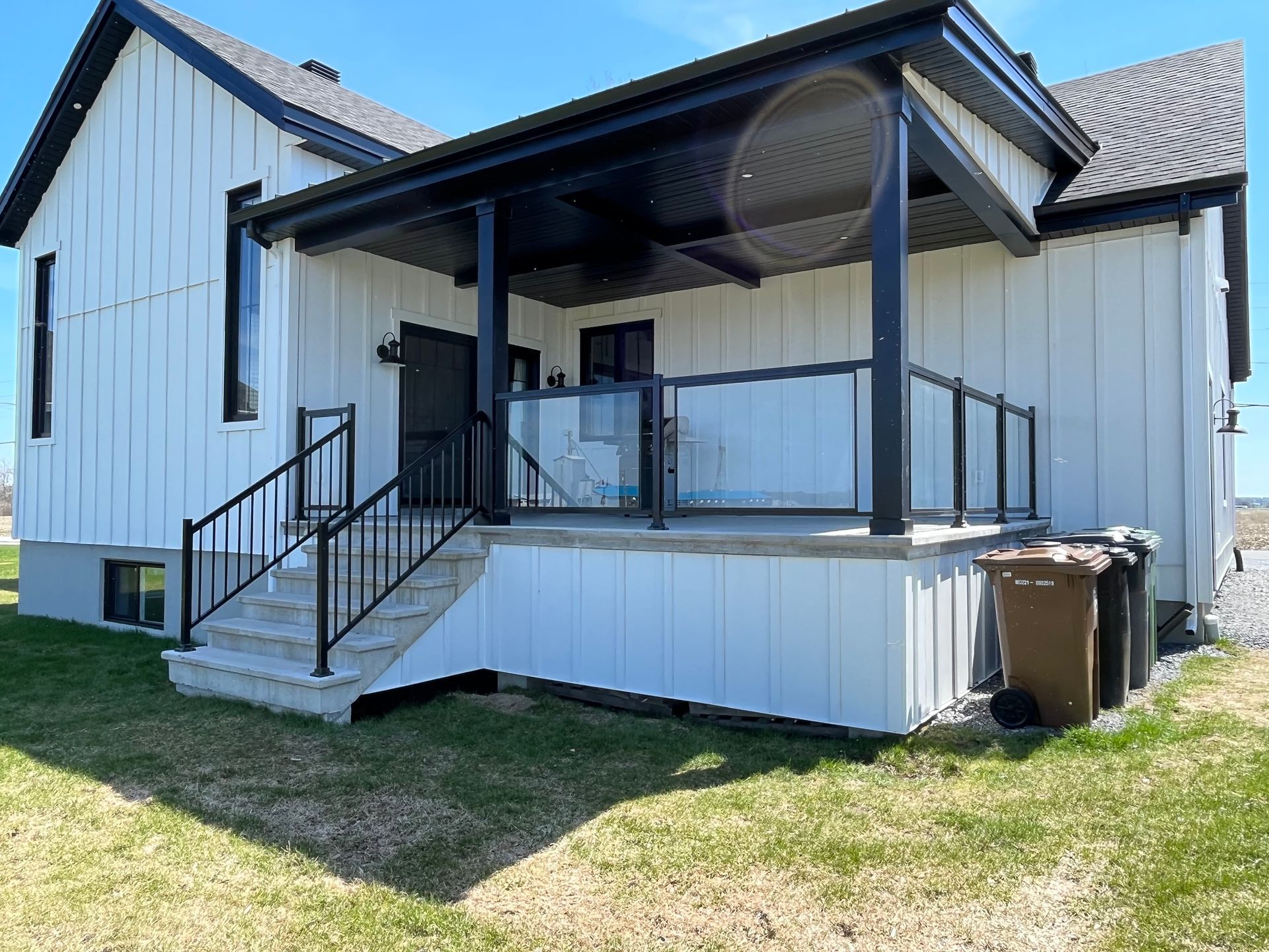 Une maison blanche avec un porche et des escaliers noirs.