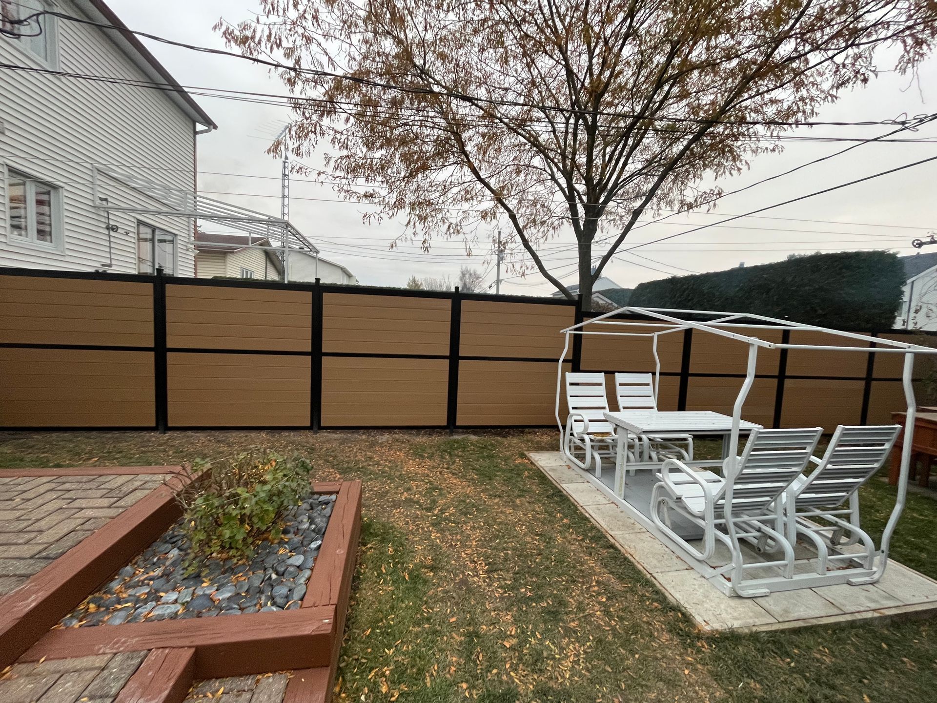 Une cour arrière avec une clôture en bois, une table et des chaises
