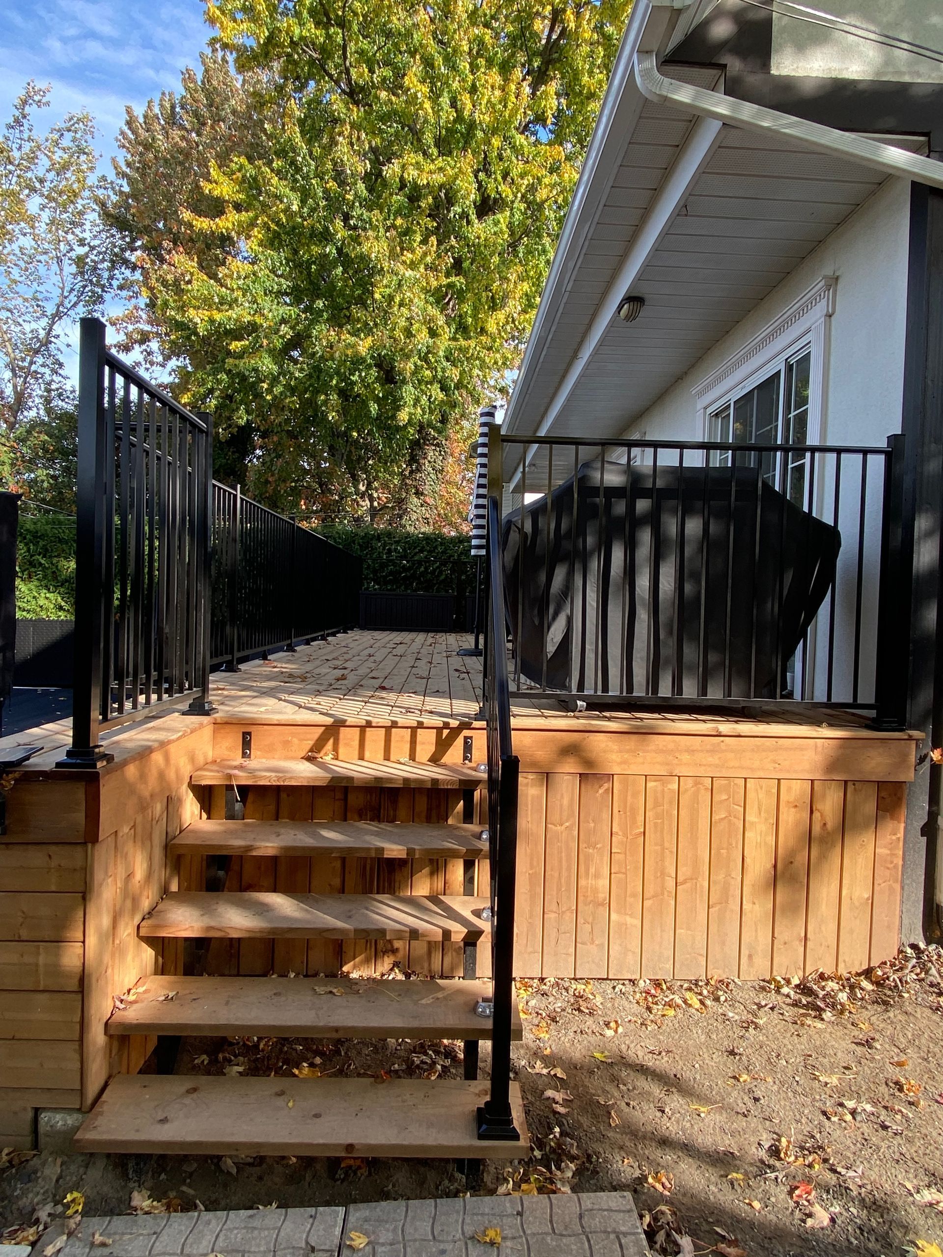 Une terrasse en bois avec des escaliers qui y mènent à côté d'une maison.