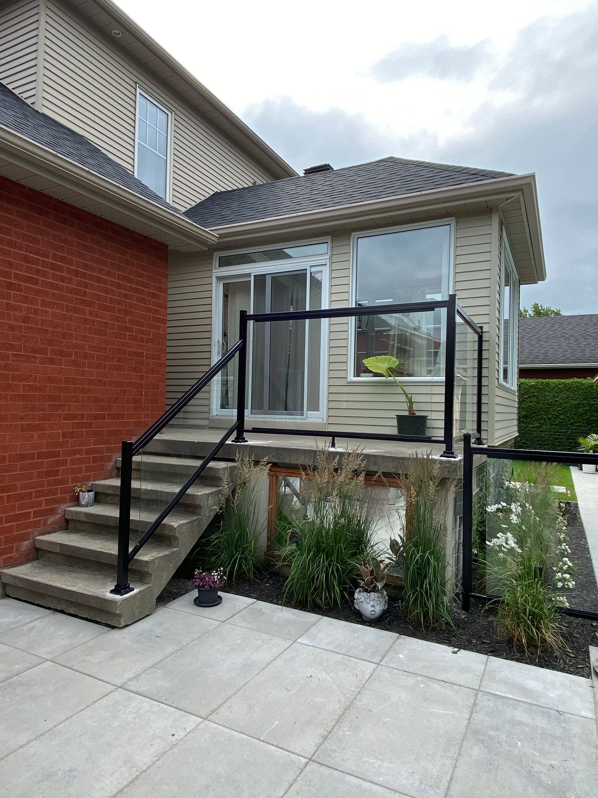 Une maison avec des escaliers et une balustrade en verre devant.