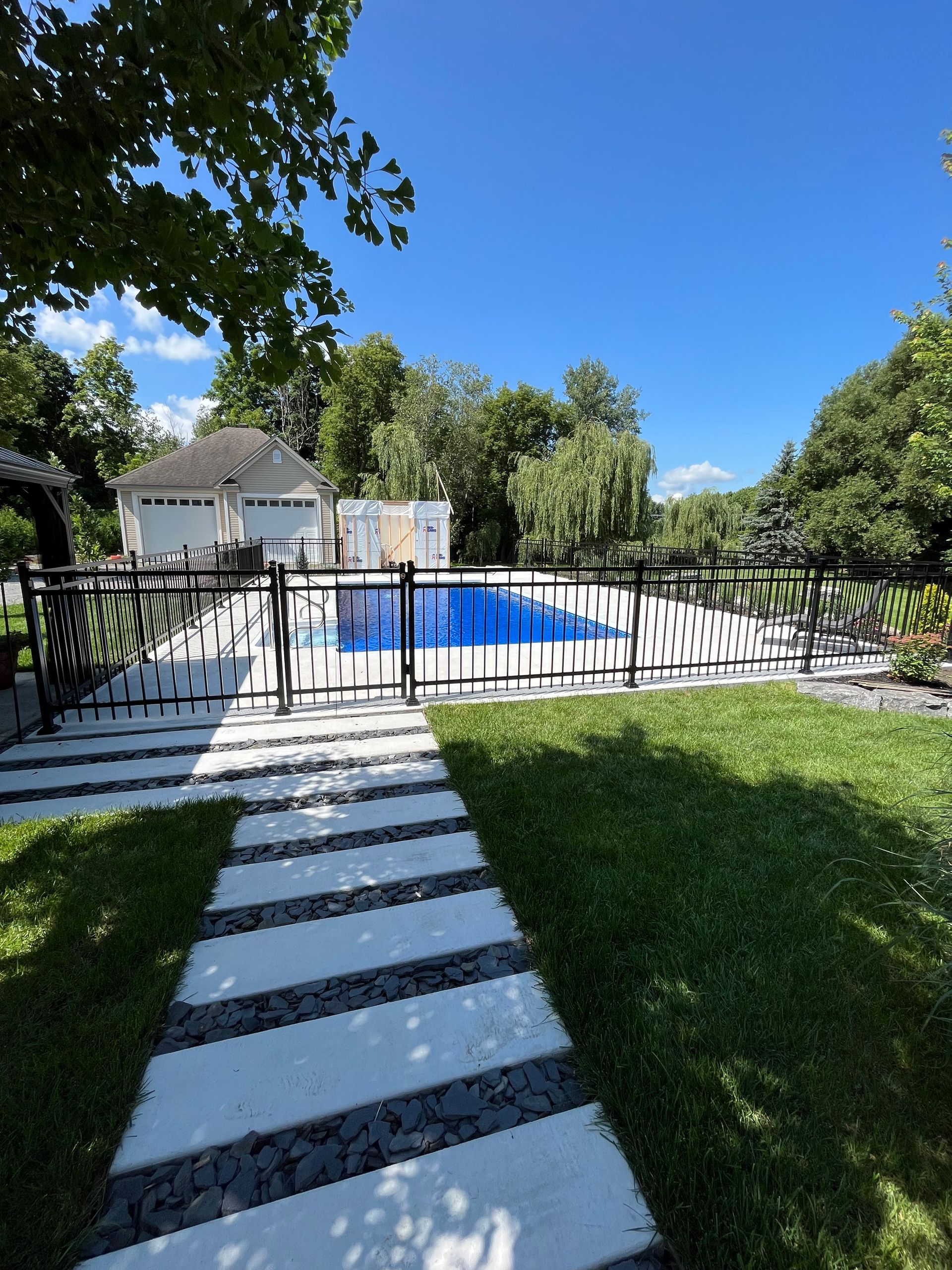 Une passerelle menant à une piscine avec une maison en arrière-plan