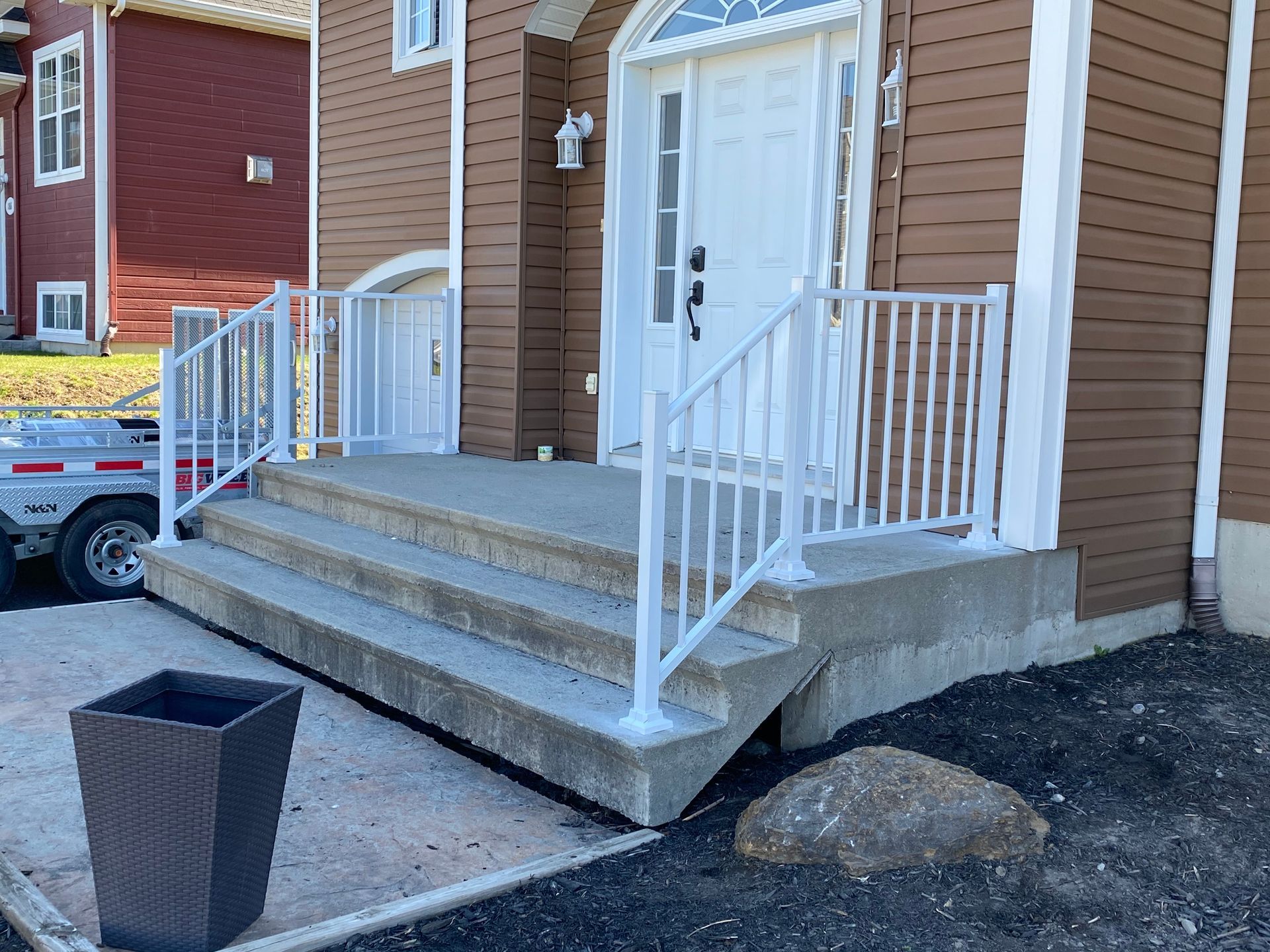 La façade d'une maison avec des escaliers et une balustrade blanche.