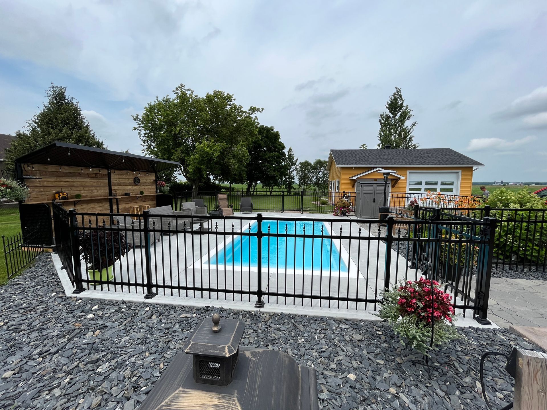Une clôture entoure une grande piscine dans une cour arrière.