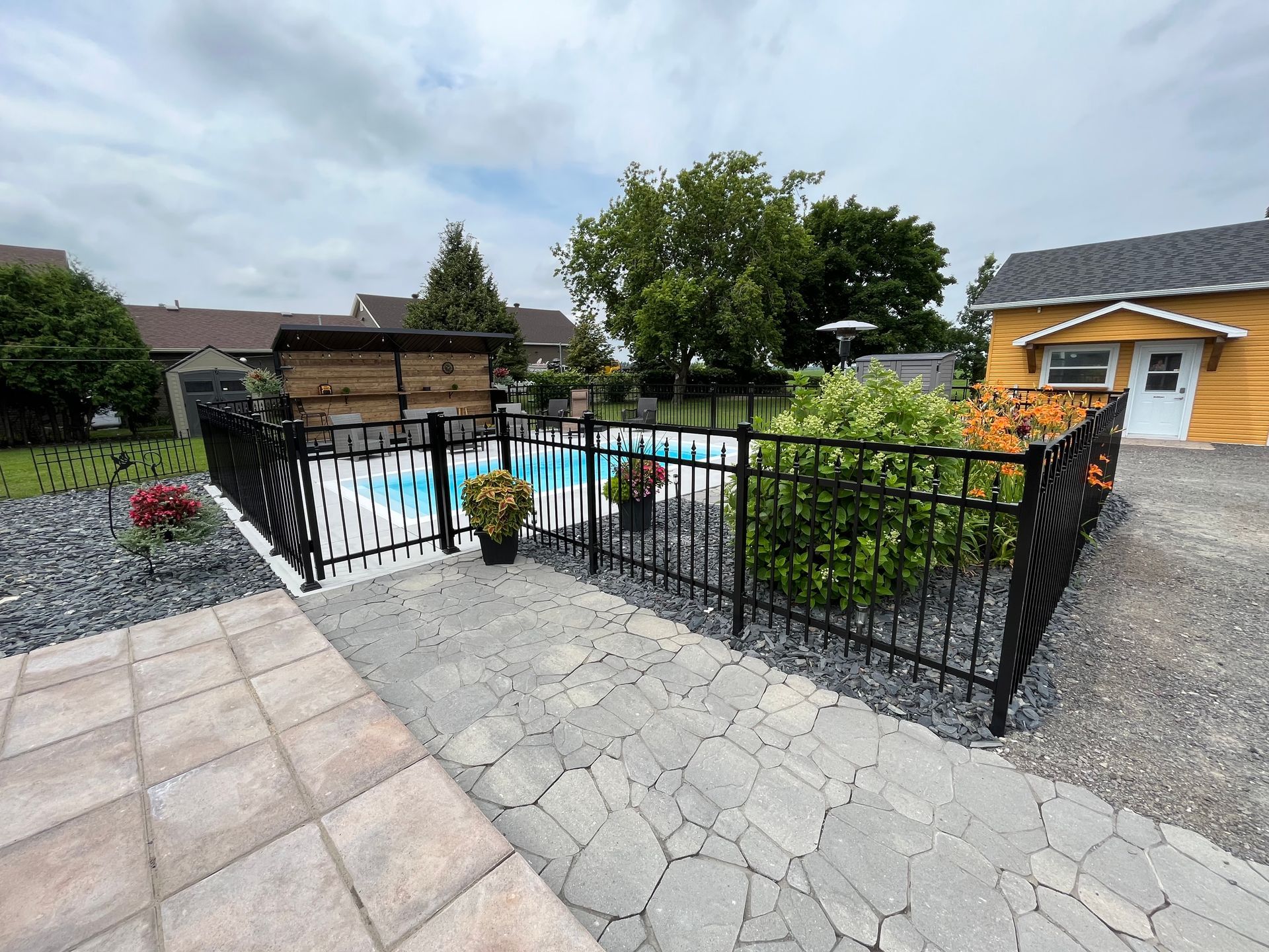 Une clôture entoure une piscine dans l'arrière-cour d'une maison.