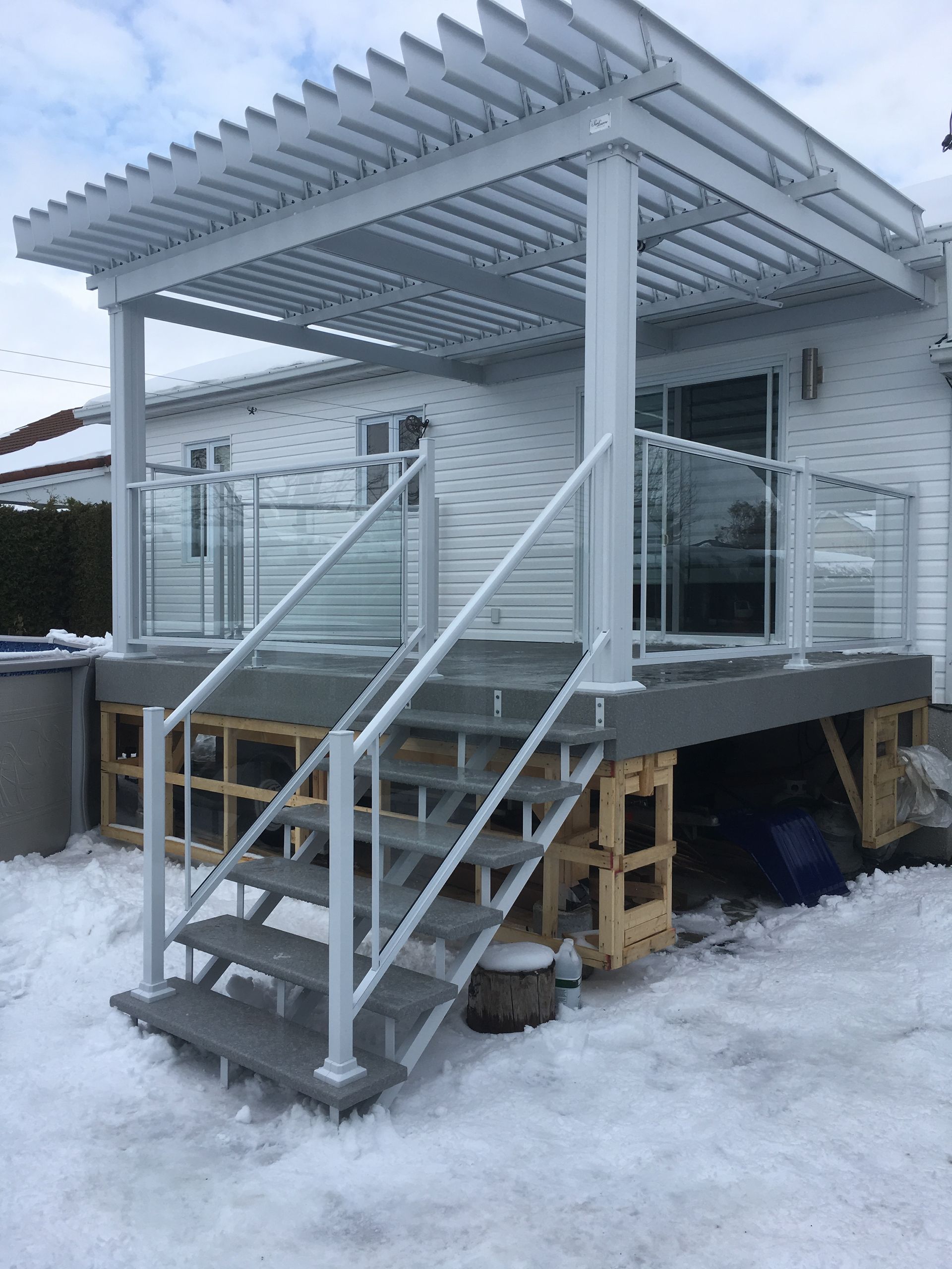 Une maison blanche avec une terrasse et des escaliers dans la neige.