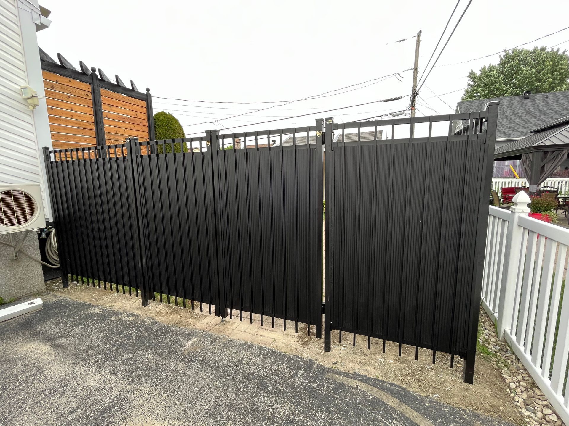 Une clôture noire avec une palissade blanche à côté d'une maison.