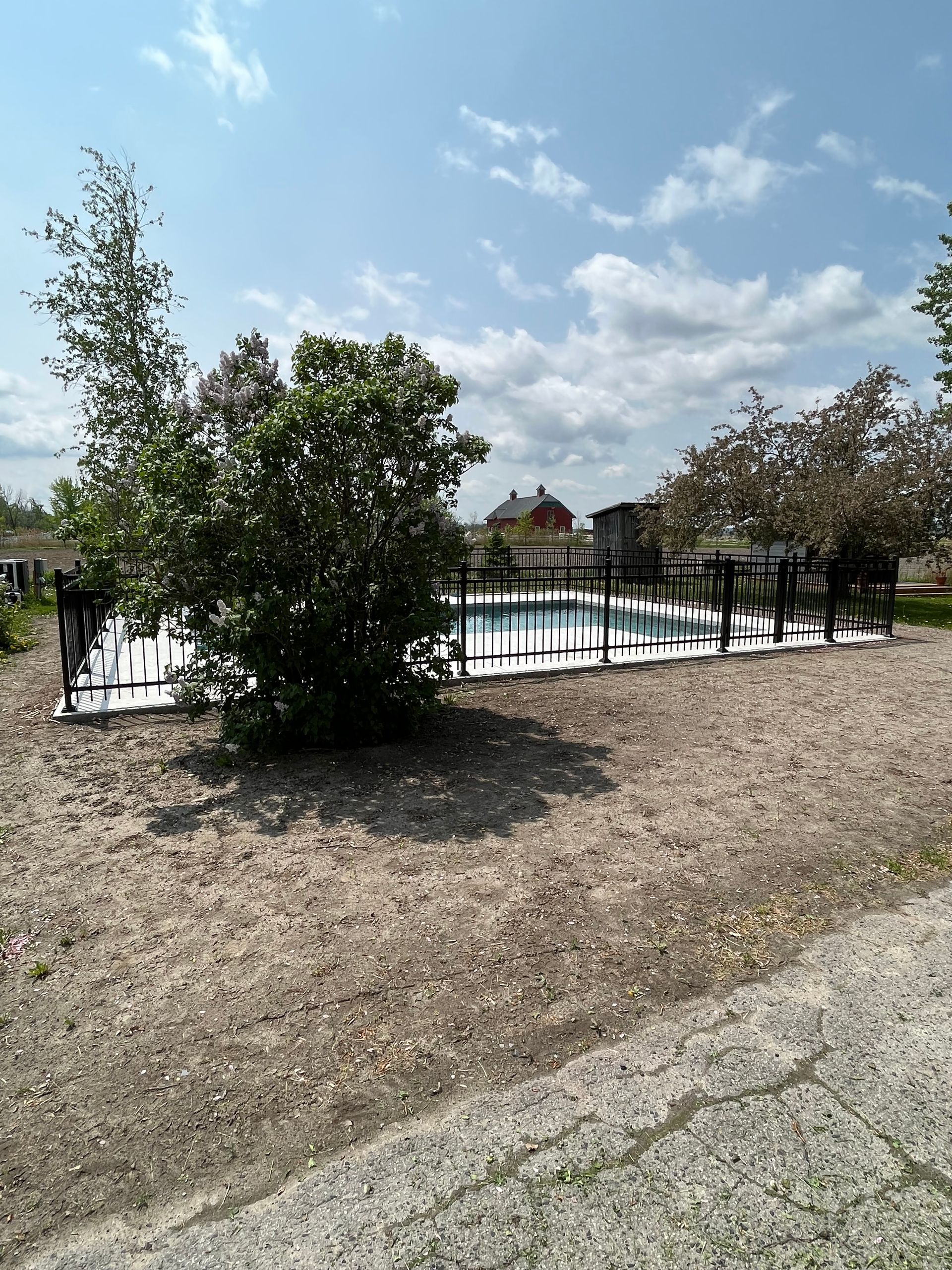 Un espace clôturé avec une piscine en arrière-plan