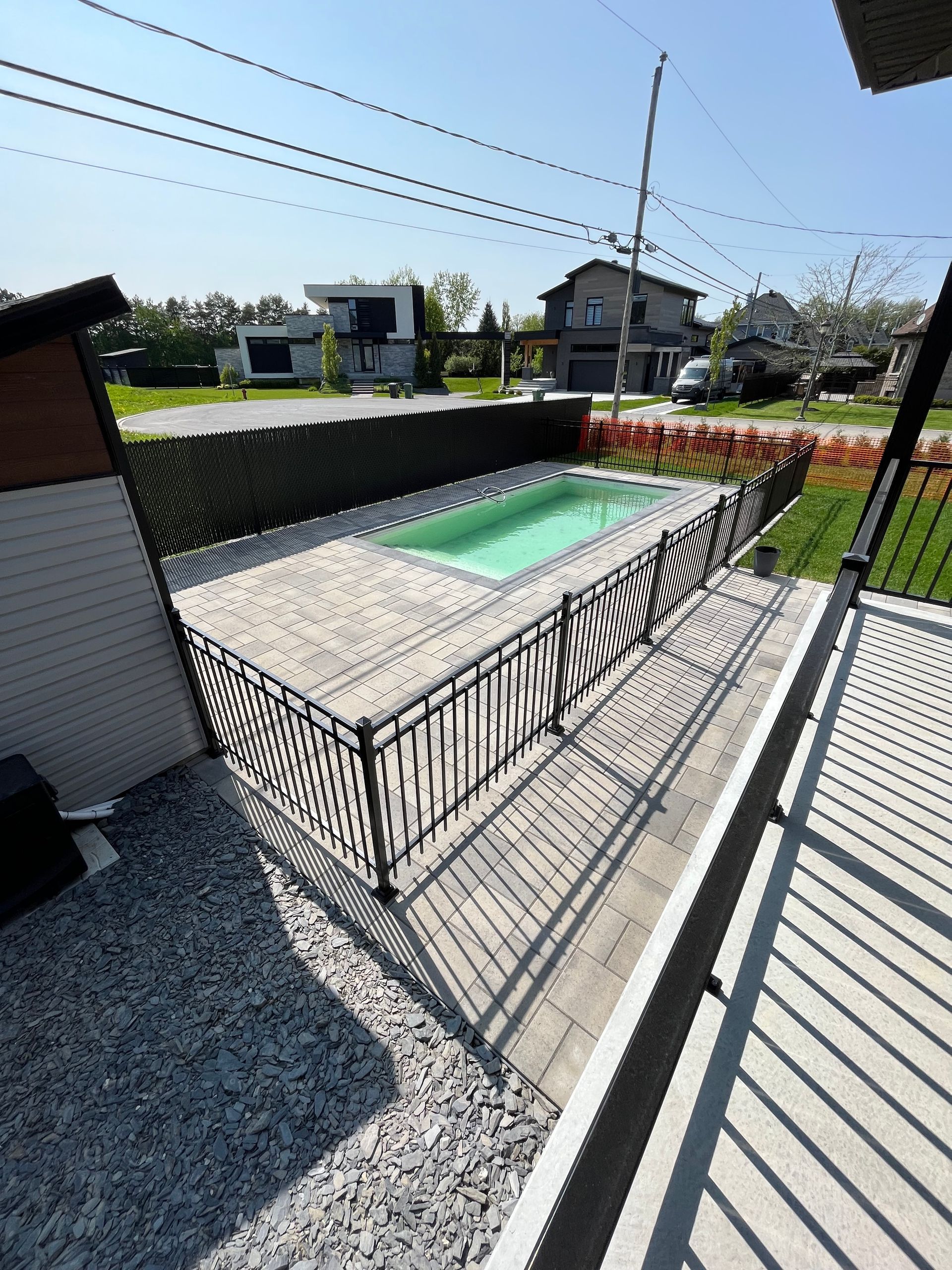 Une petite piscine est entourée de gravier et d'une clôture.