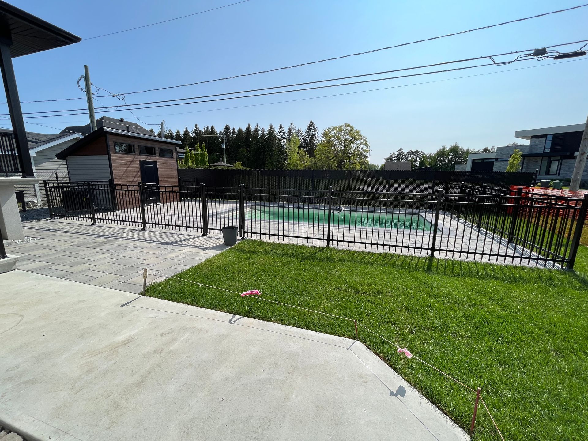 Une cour arrière avec une clôture et une piscine en arrière-plan