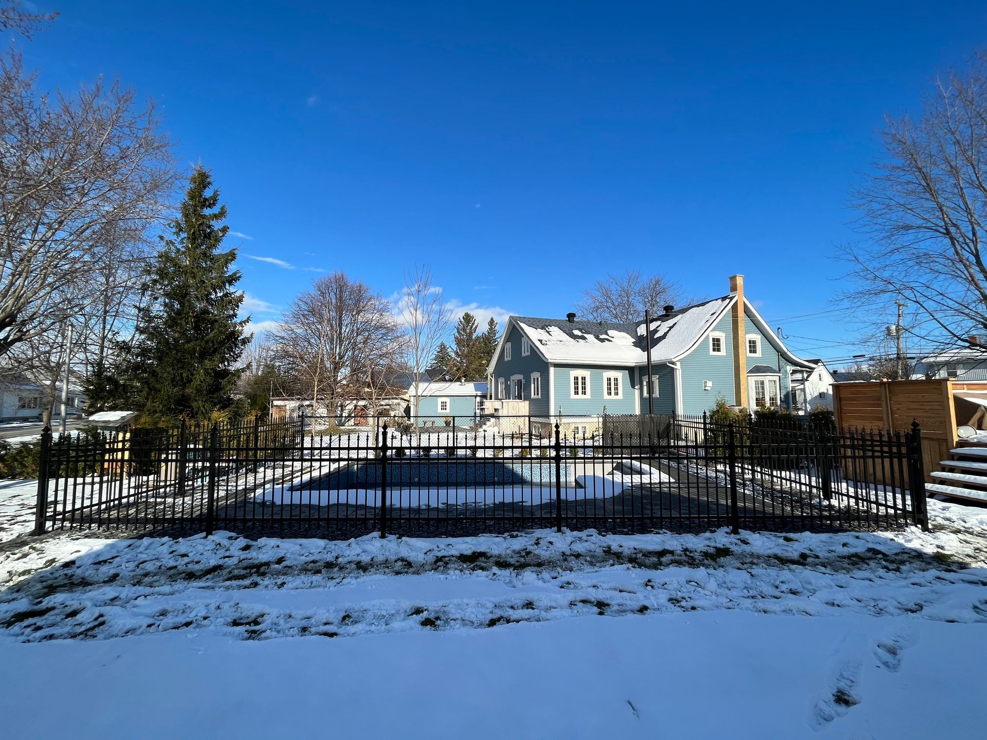 Il y a une piscine dans l'arrière-cour d'une maison entourée de neige.