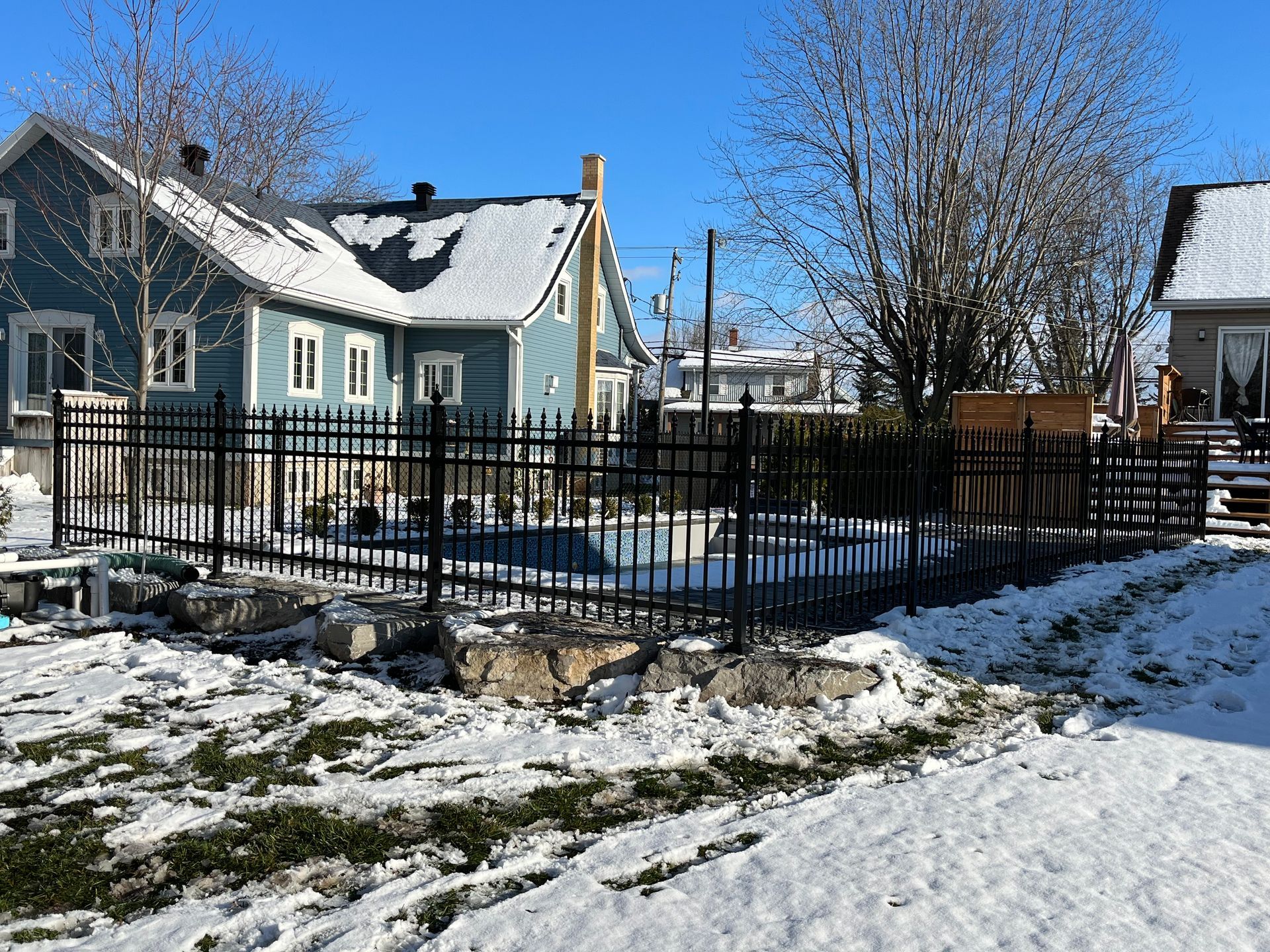 Une maison avec une piscine dans l'arrière-cour est entourée de neige et d'une clôture.