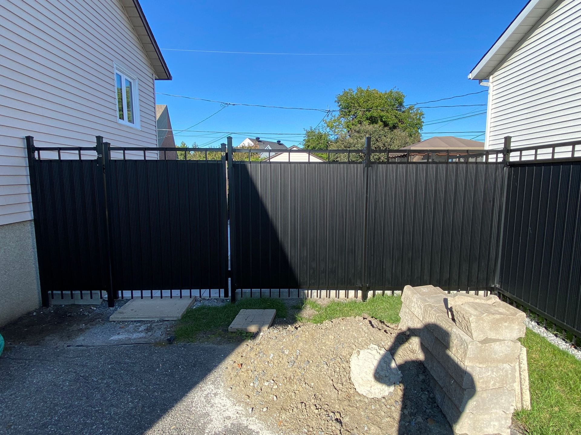 Une clôture noire se trouve dans l'arrière-cour d'une maison.