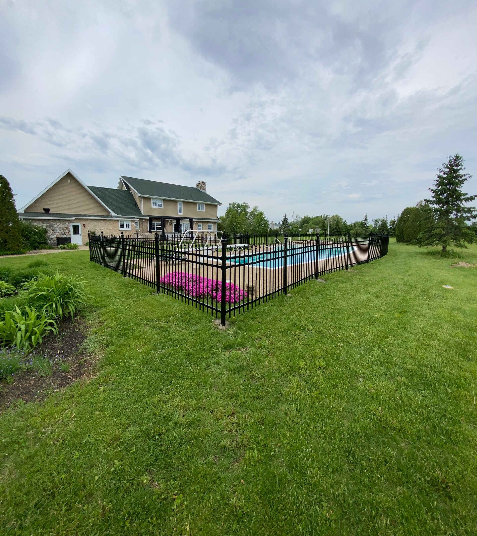 Une grande maison avec une piscine dans l'arrière-cour derrière une clôture.