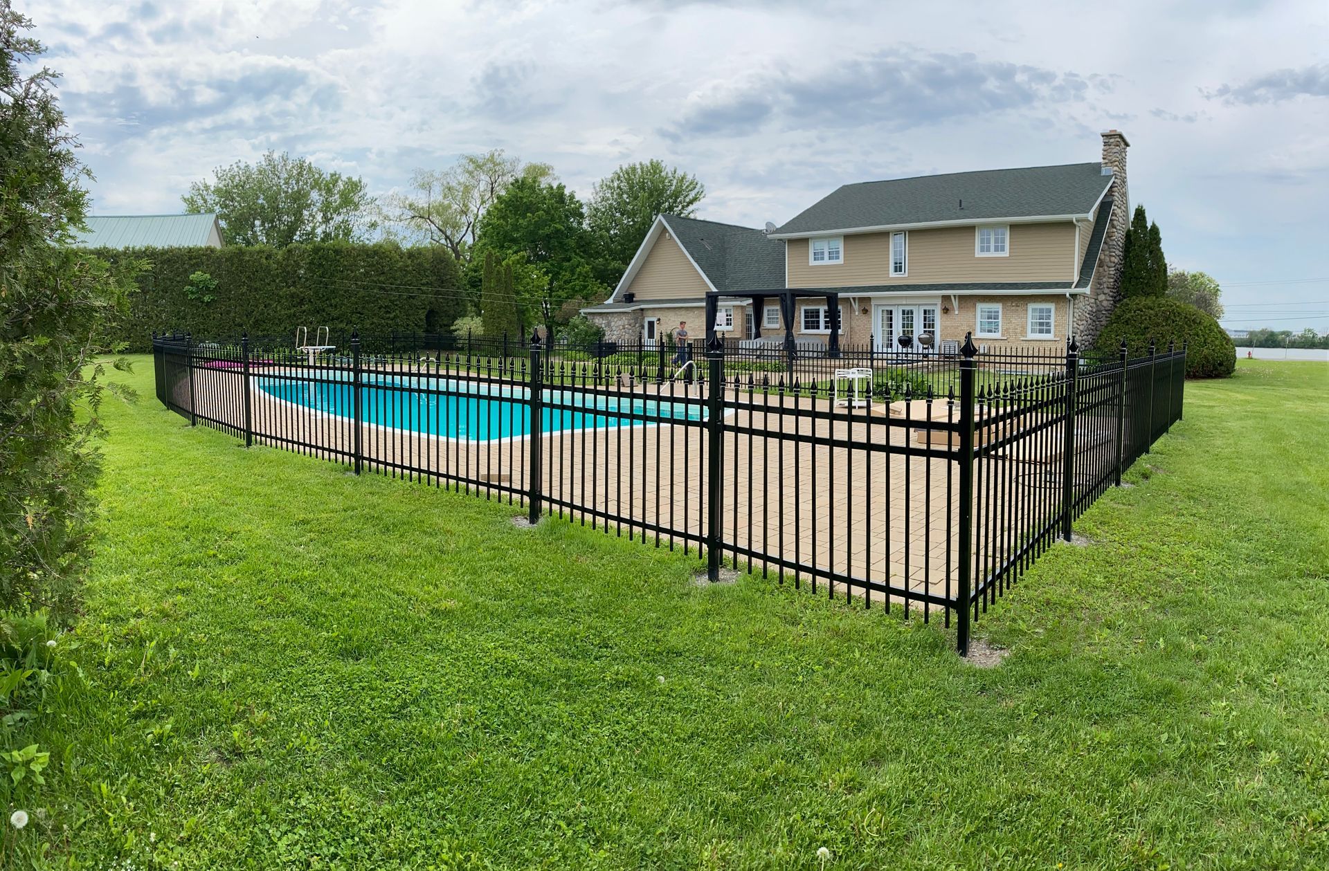 Une grande maison avec une piscine derrière une clôture.