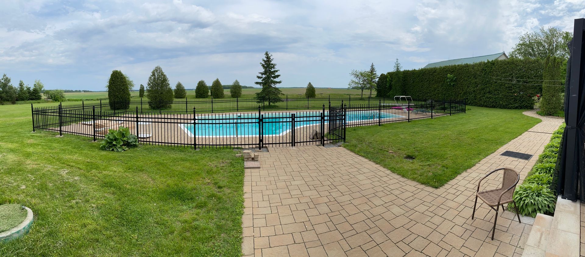 Une grande piscine est entourée d'une clôture dans une cour arrière.