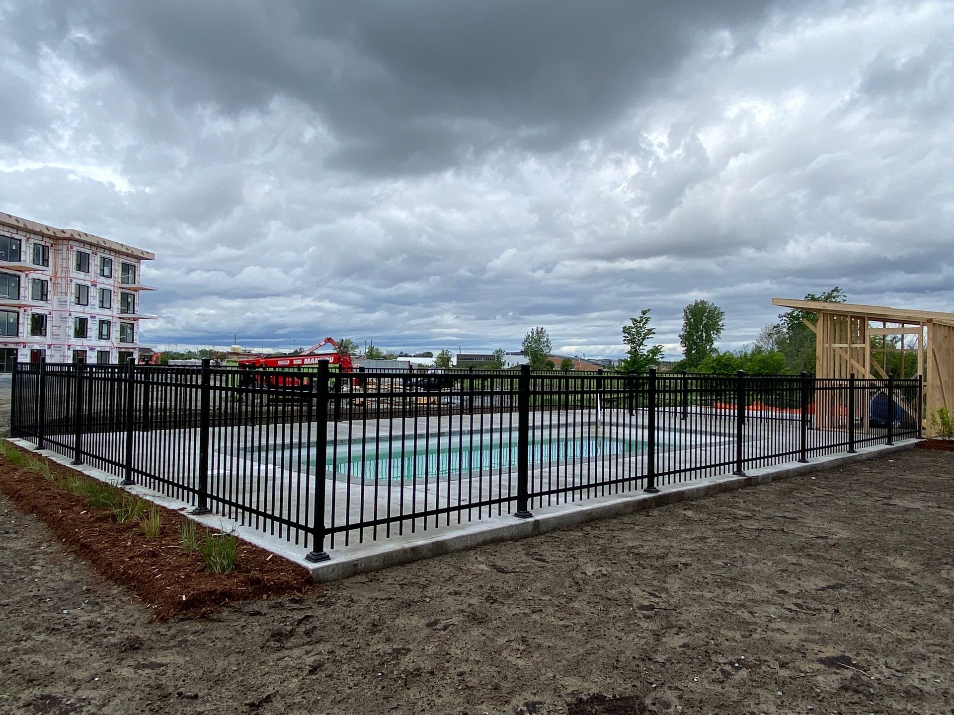 Une clôture autour d'une piscine avec un ciel nuageux en arrière-plan.
