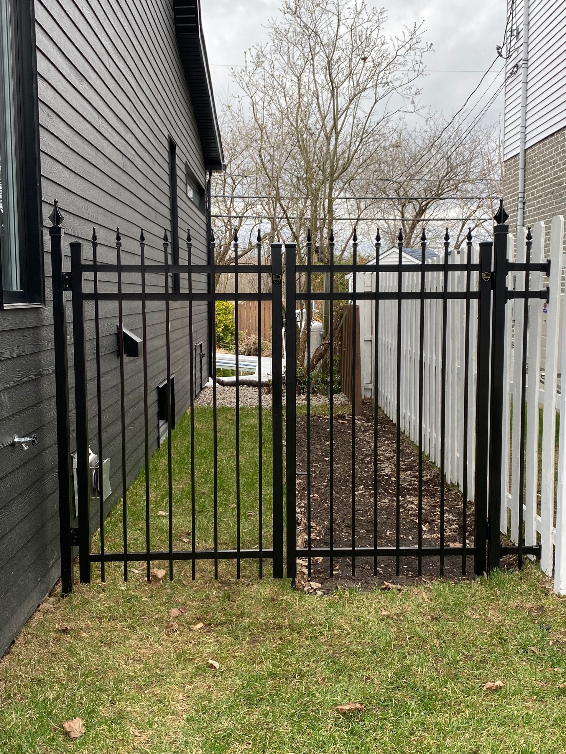 Une clôture noire avec une palissade blanche devant une maison.