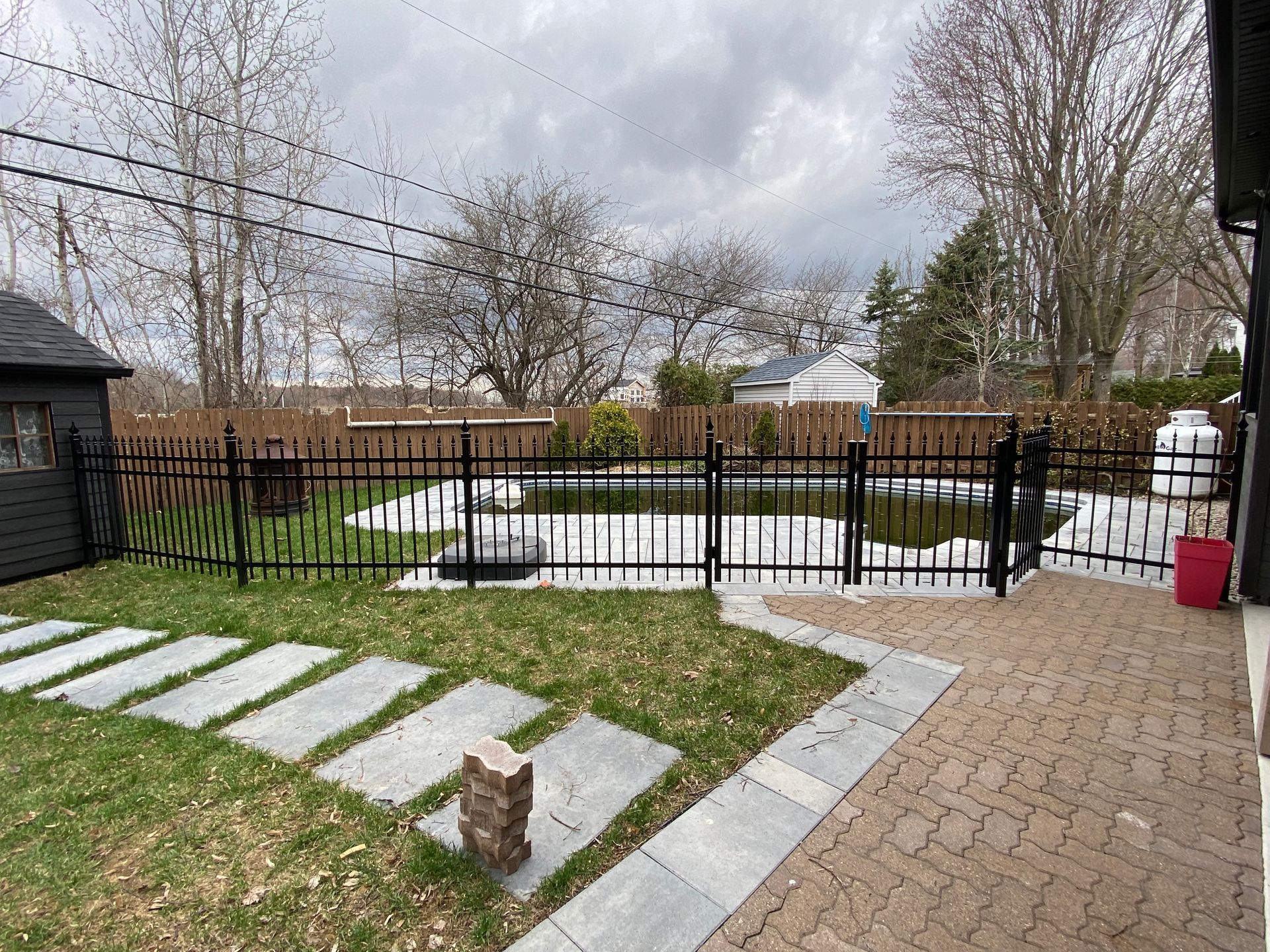 Une cour arrière avec une clôture et une piscine en arrière-plan.