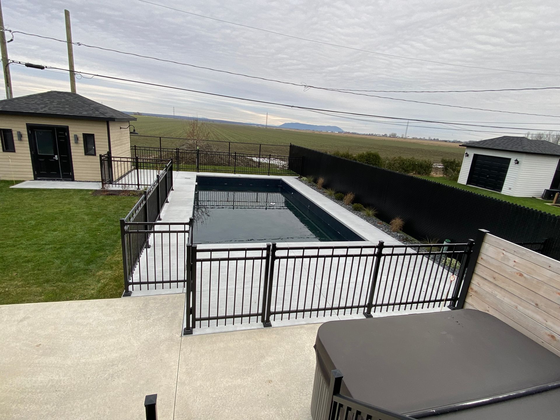 Une grande piscine est entourée d'une clôture et d'un jacuzzi.