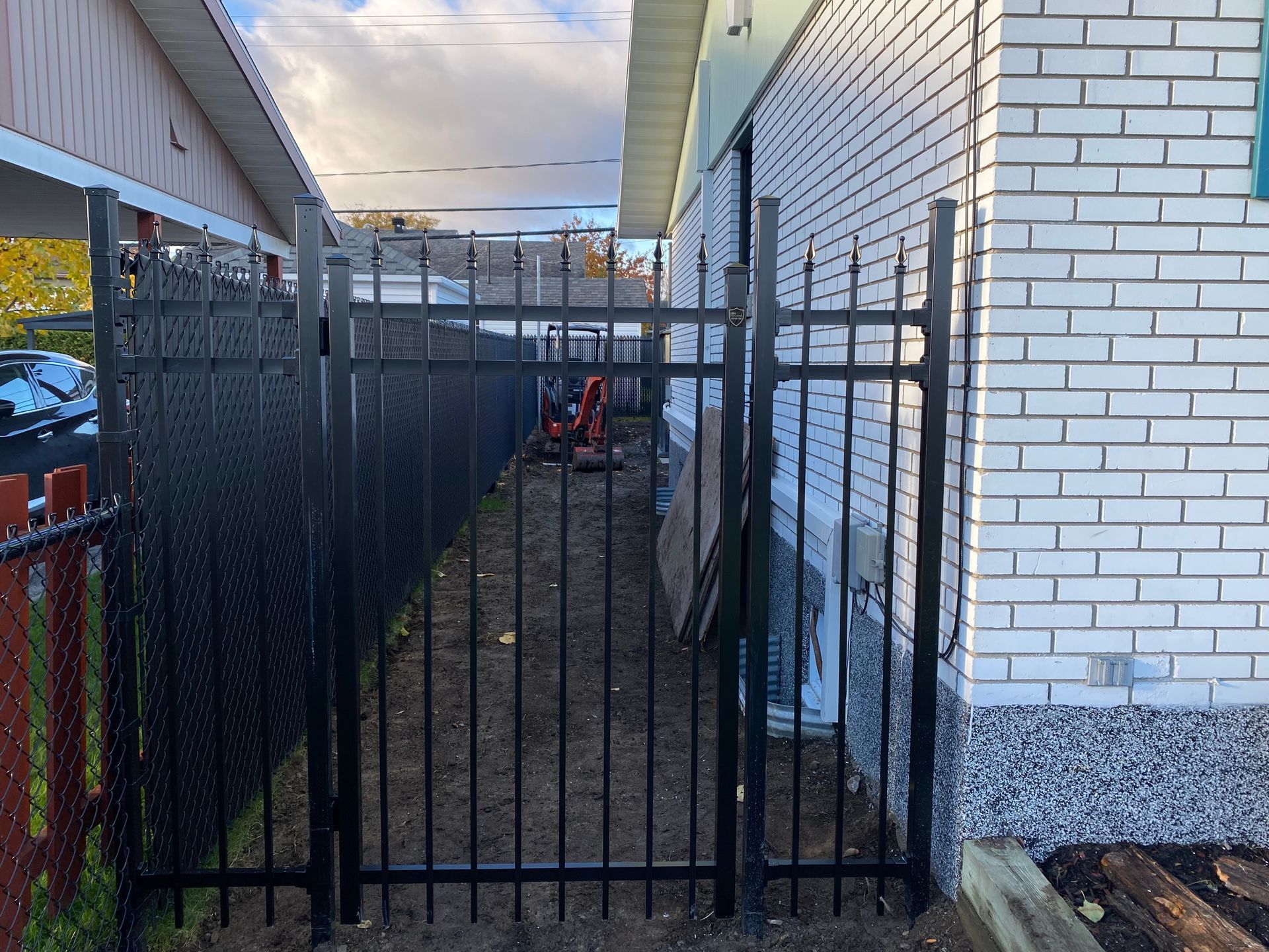 Une clôture noire entoure un bâtiment en briques blanches.
