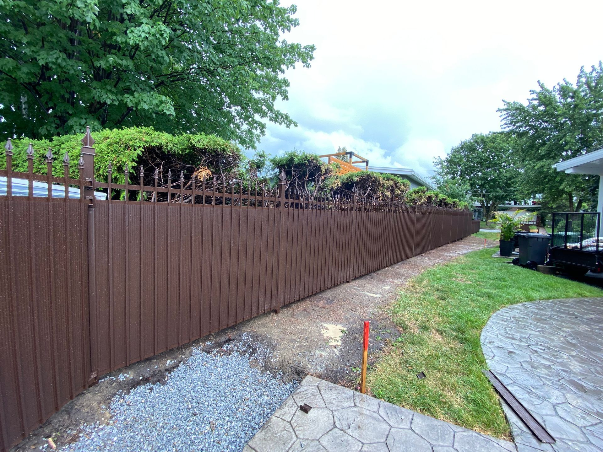 Une clôture en bois marron est entourée d'herbe et d'arbres dans une cour arrière.