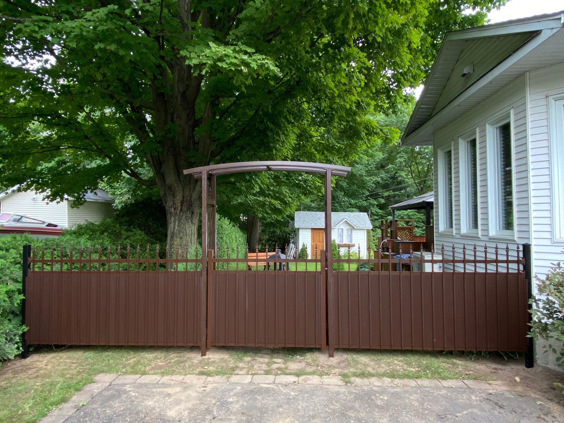 Une clôture marron est devant une maison blanche