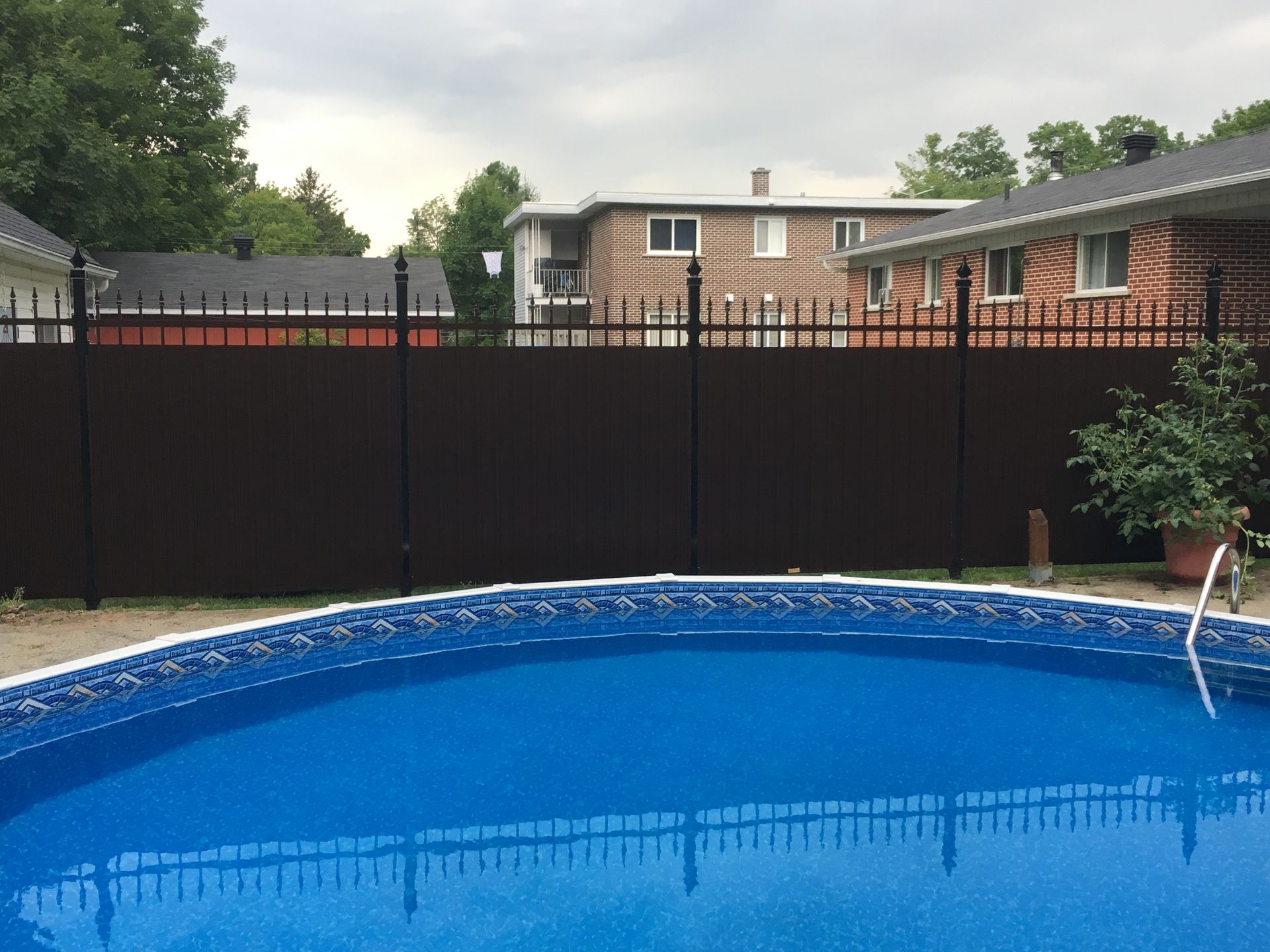 Une piscine avec une clôture qui l'entoure et une maison en arrière-plan.