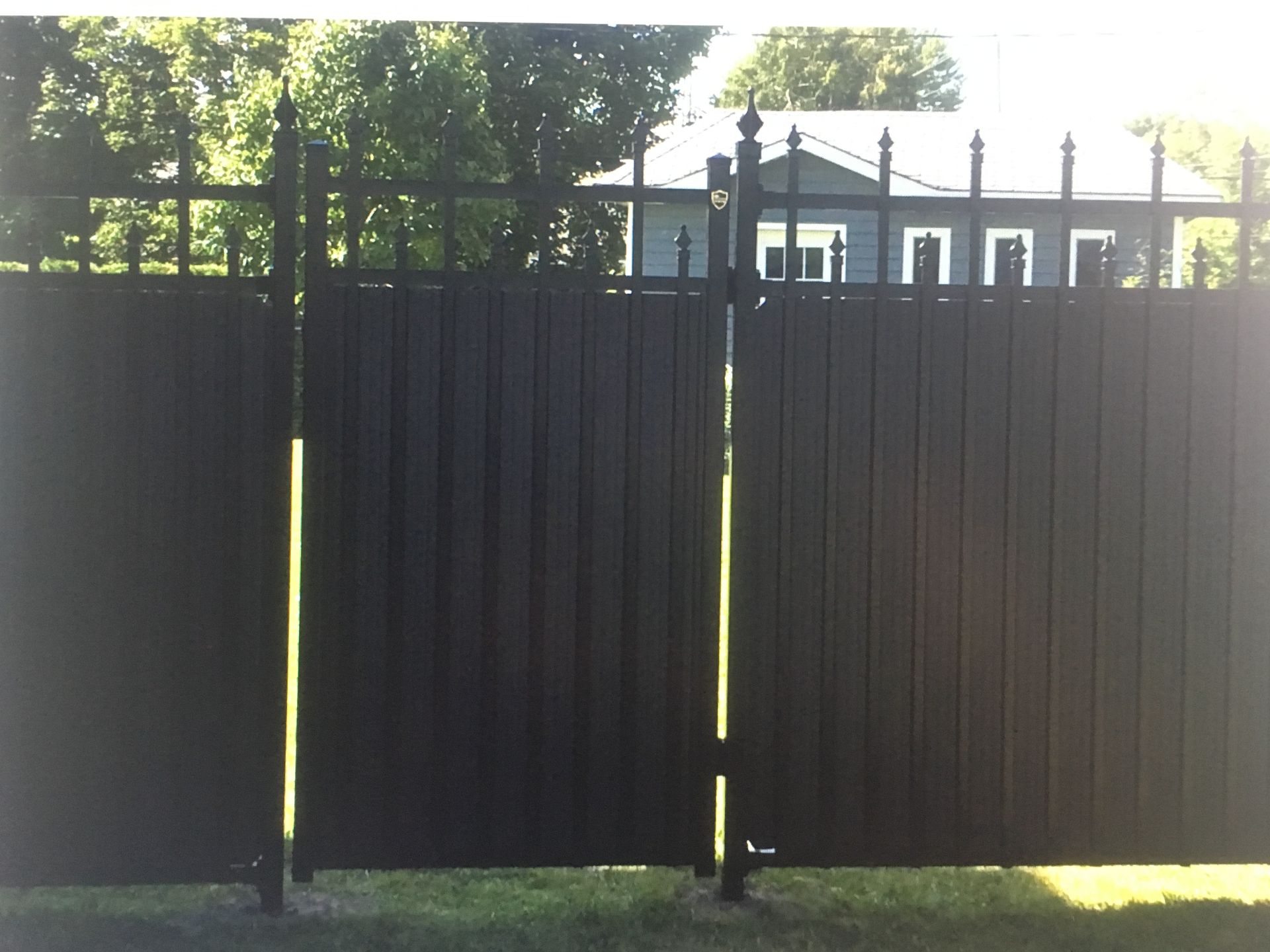 Une clôture noire avec une maison en arrière-plan