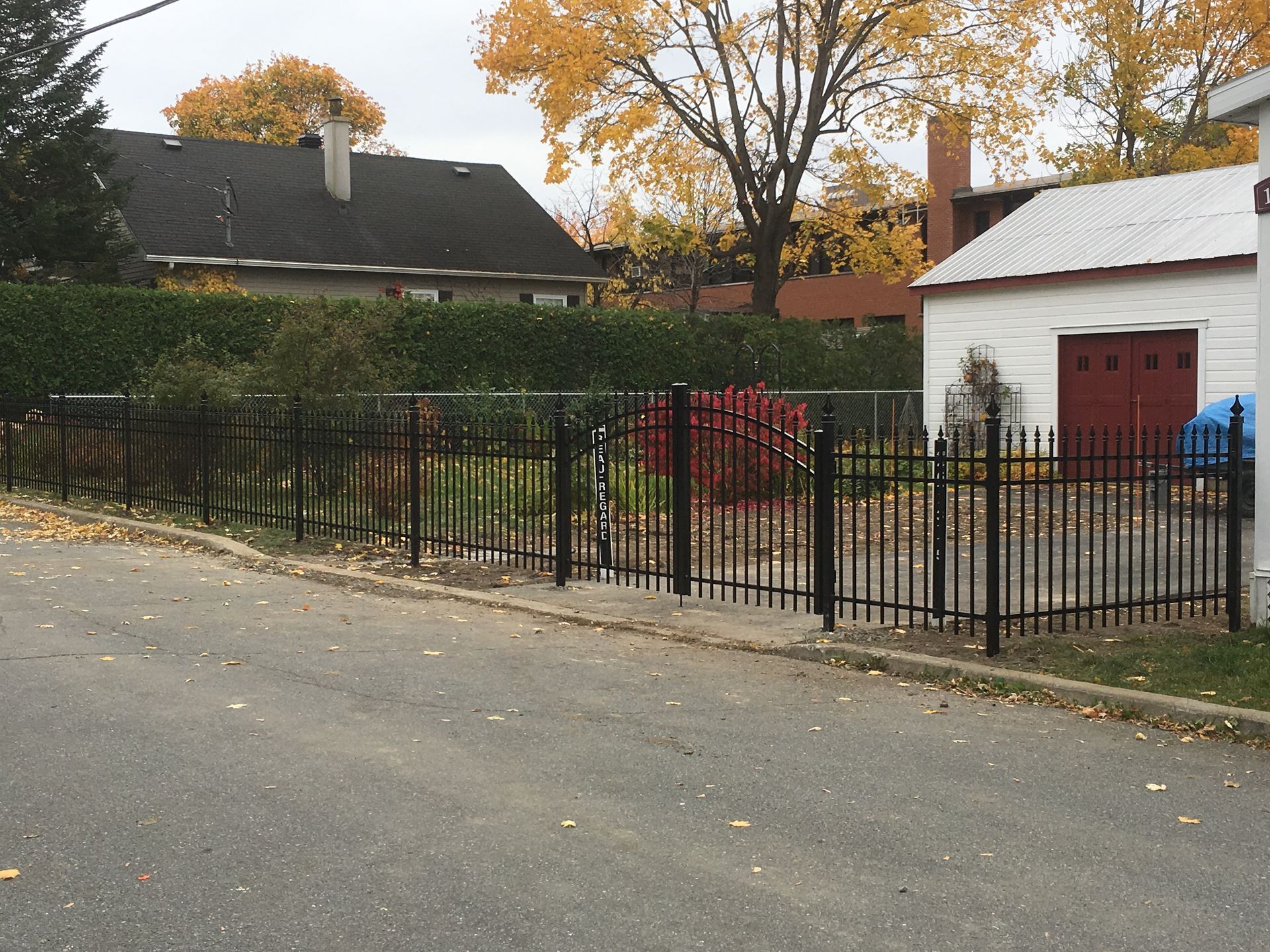 Une clôture en fer forgé noir entoure un quartier résidentiel