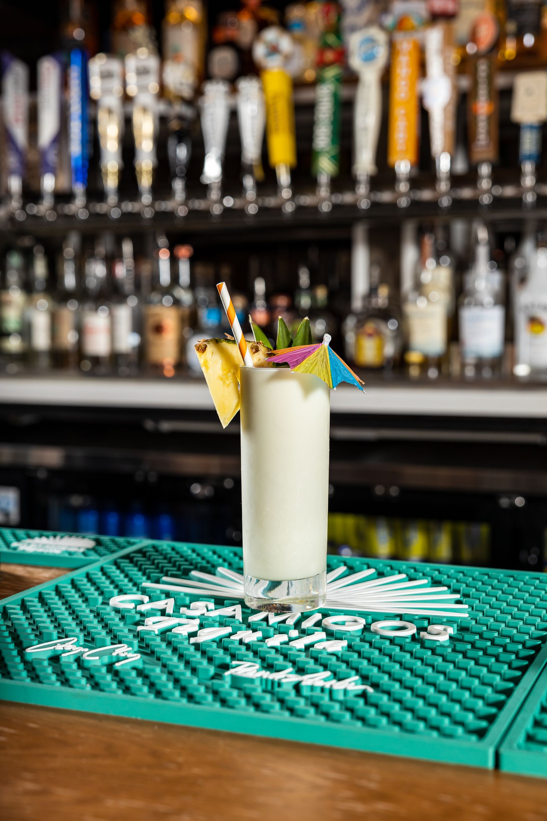 A pineapple milkshake is sitting on a green bar mat on a bar at con safos in downtown denver