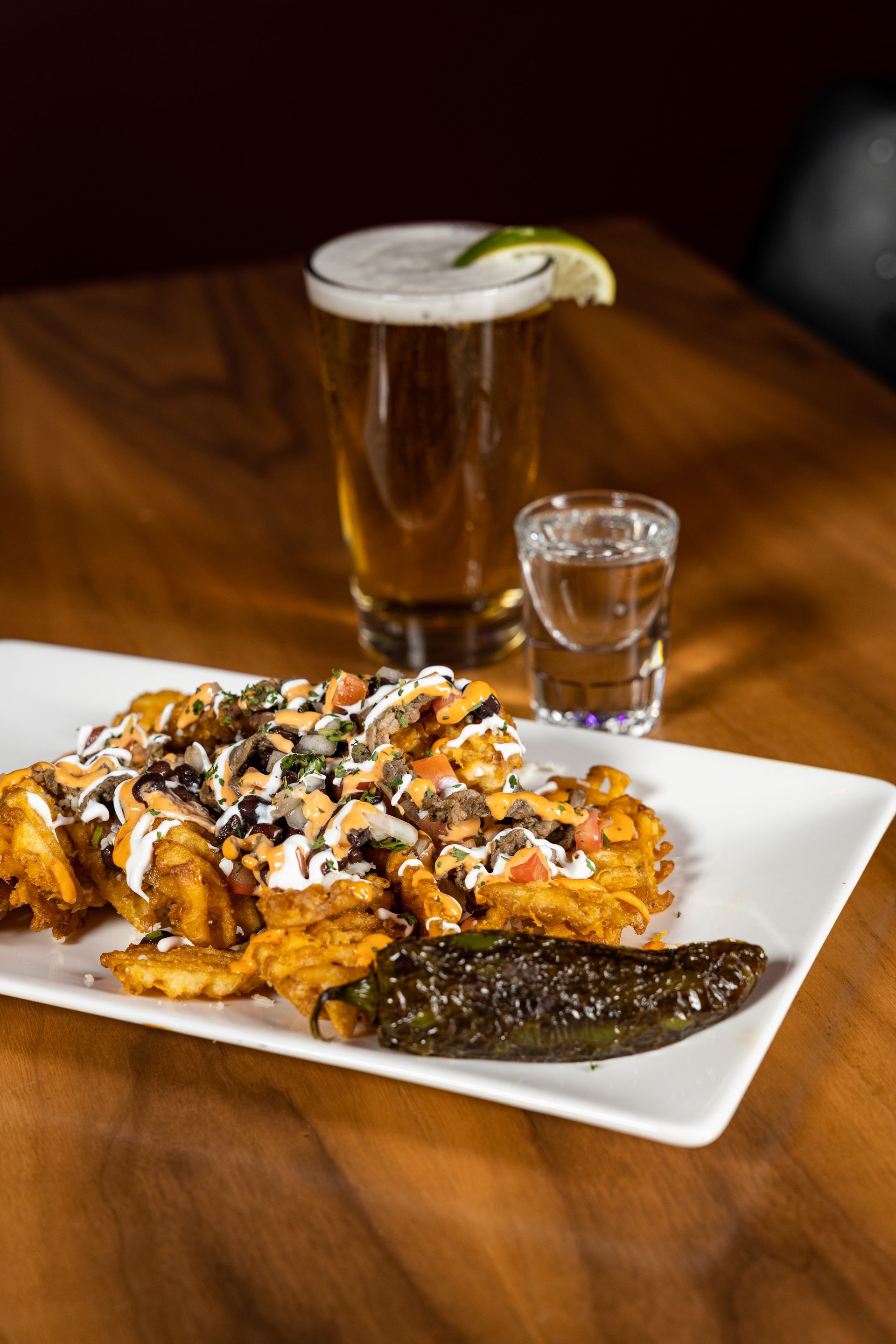 A plate of food and a glass of beer on a wooden table at con safos in denver colorado