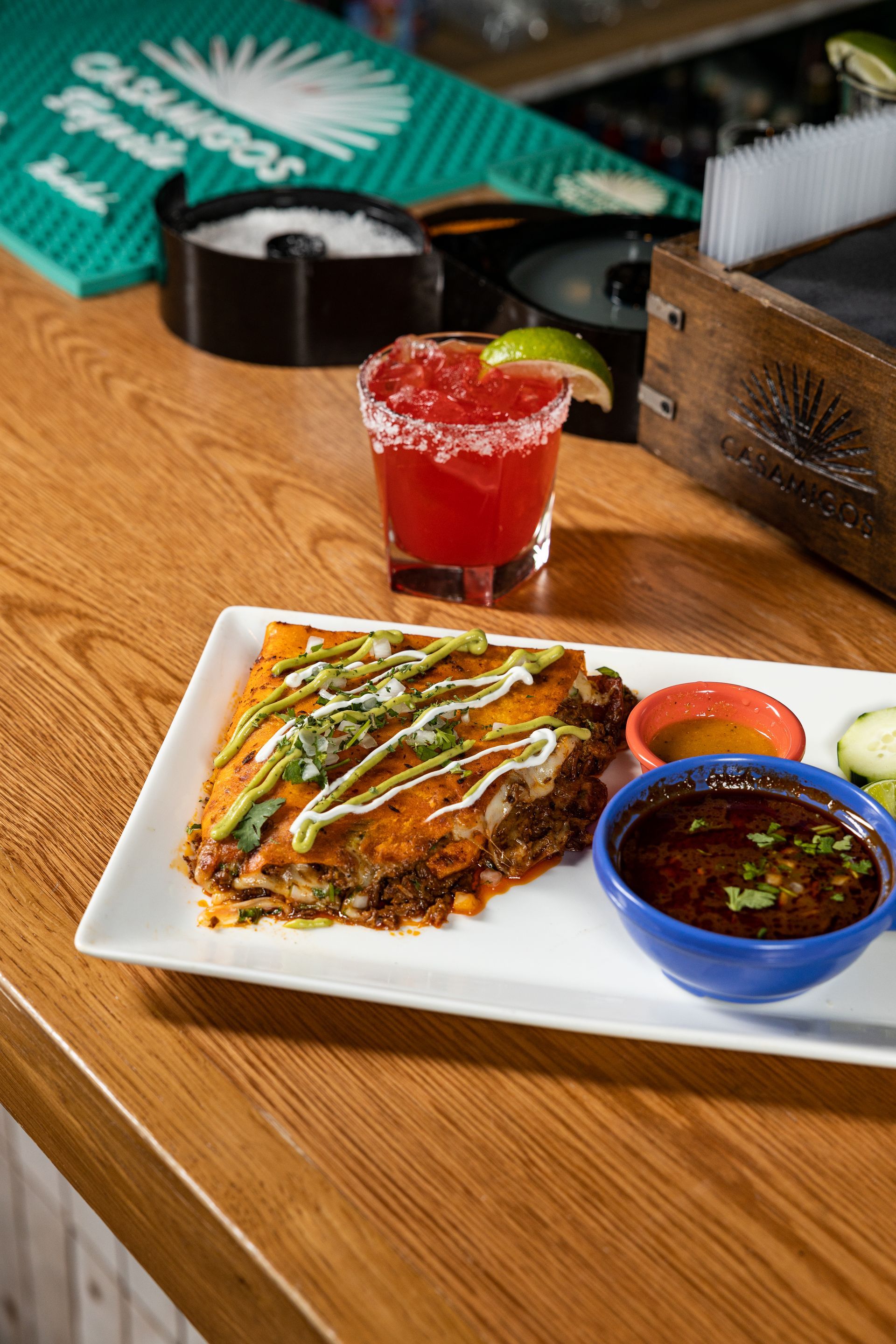 A plate of food and a drink on a wooden table at con safos in downtown denver