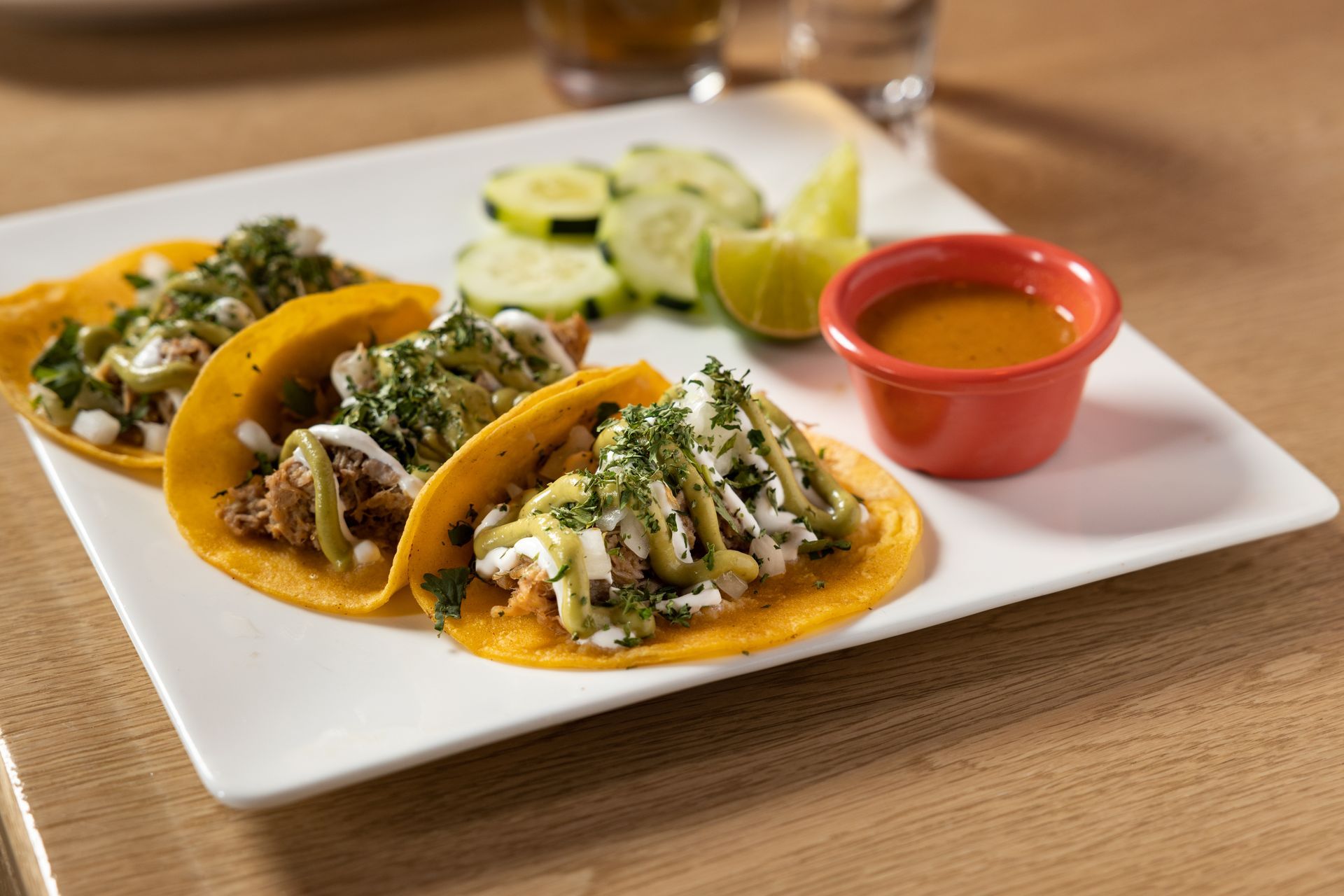 A white plate topped with three tacos and a small bowl of sauce at con safos in denver colorado