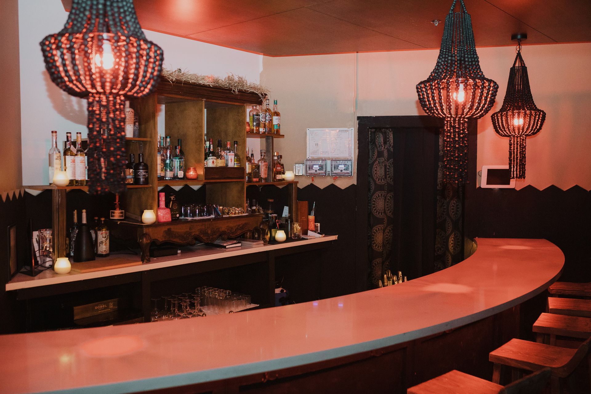 A bar with a long counter and stools and a chandelier hanging from the ceiling at agua bendita, a speakeasy in downtown denver colorado