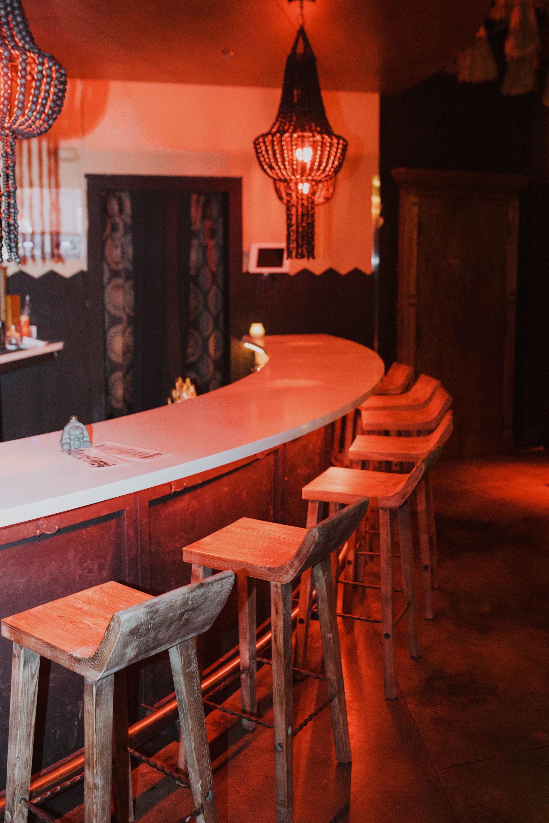 A bar with stools and a chandelier hanging from the ceiling at agua bendita, a speakeasy in downtown denver colorado