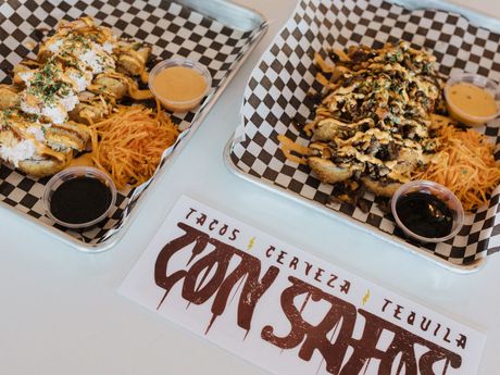 Two trays of food with a sign that says con safos, a denver colorado mexican restaurant near coors field