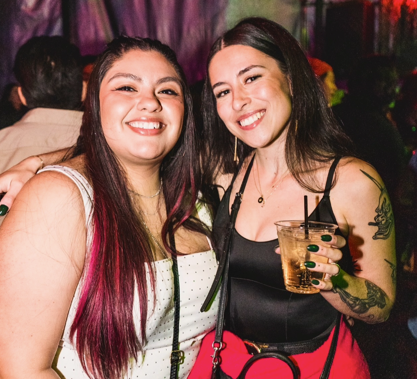 Two women are posing for a picture and one is holding a drink at el patio in denver colorado near coors field