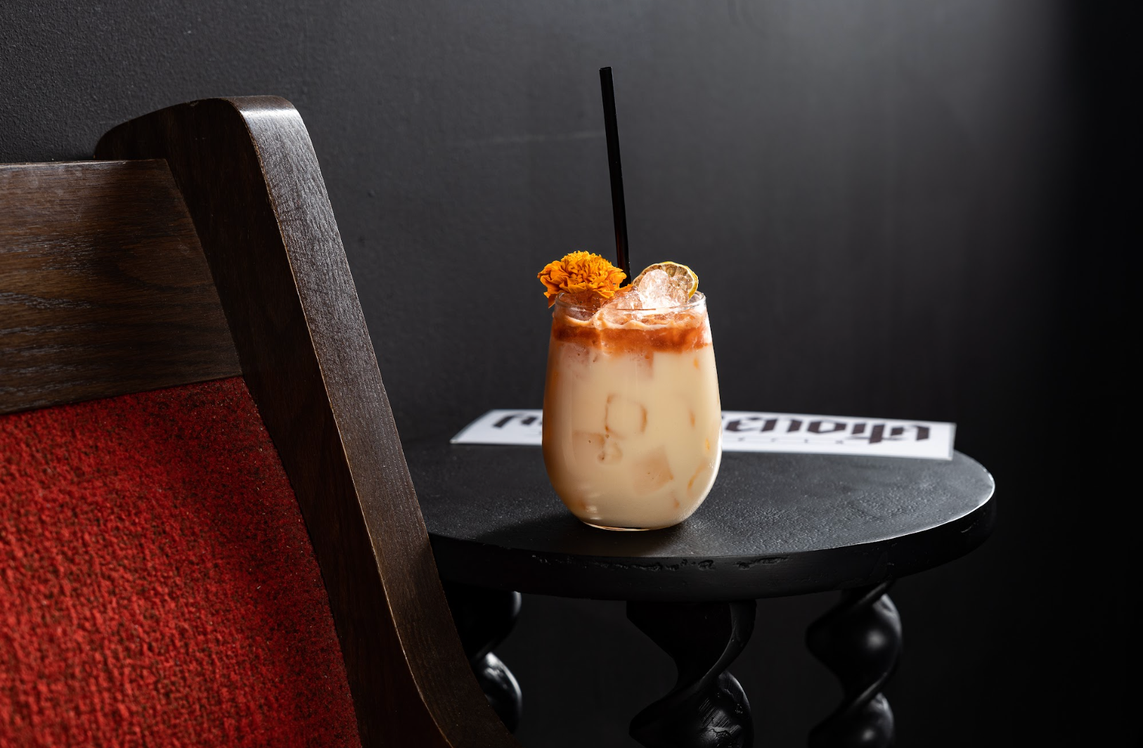 A drink in a glass on a table next to a chair at agua bendita in denver colorado