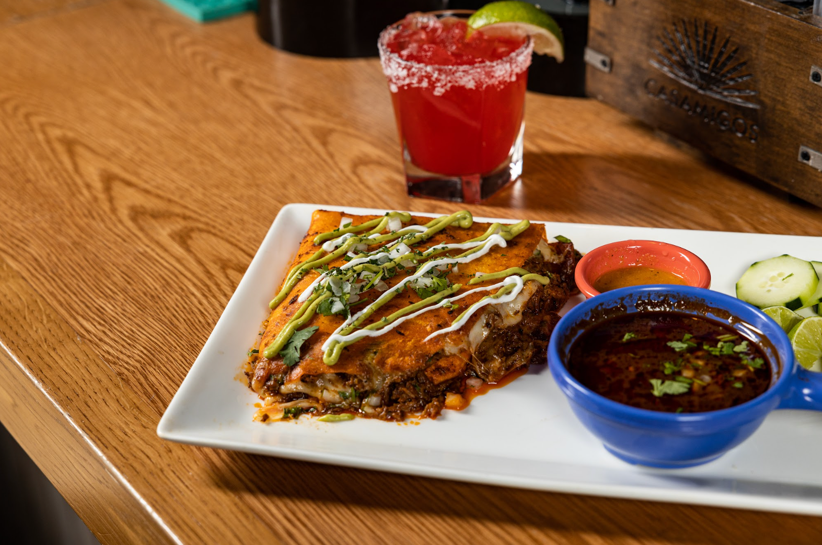 A plate of food and a drink on a wooden table at con safos in downtown denver colorado