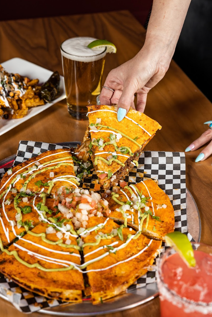 A person is taking a slice of quesadilla from a pizza at con safos in downtown denver colorado