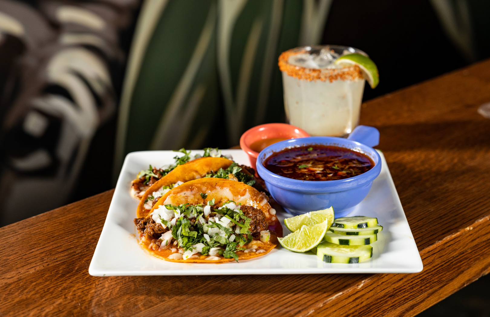 A plate of tacos and a drink on a wooden table at con safos in downtown denver colorado