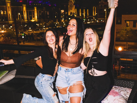 Three women are posing for a picture with their arms in the air.