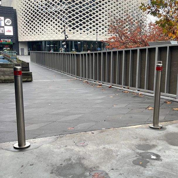 2 chrome bollards in front of a driveway
