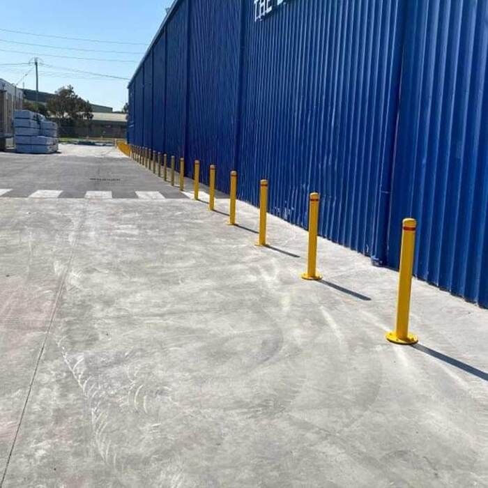 row of yellow bollards infant of shipping container