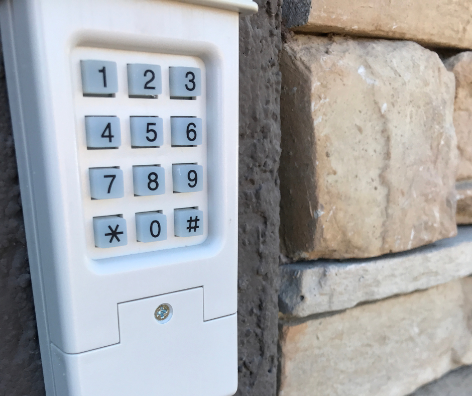 A white lock keypad is attached to a brick wall.