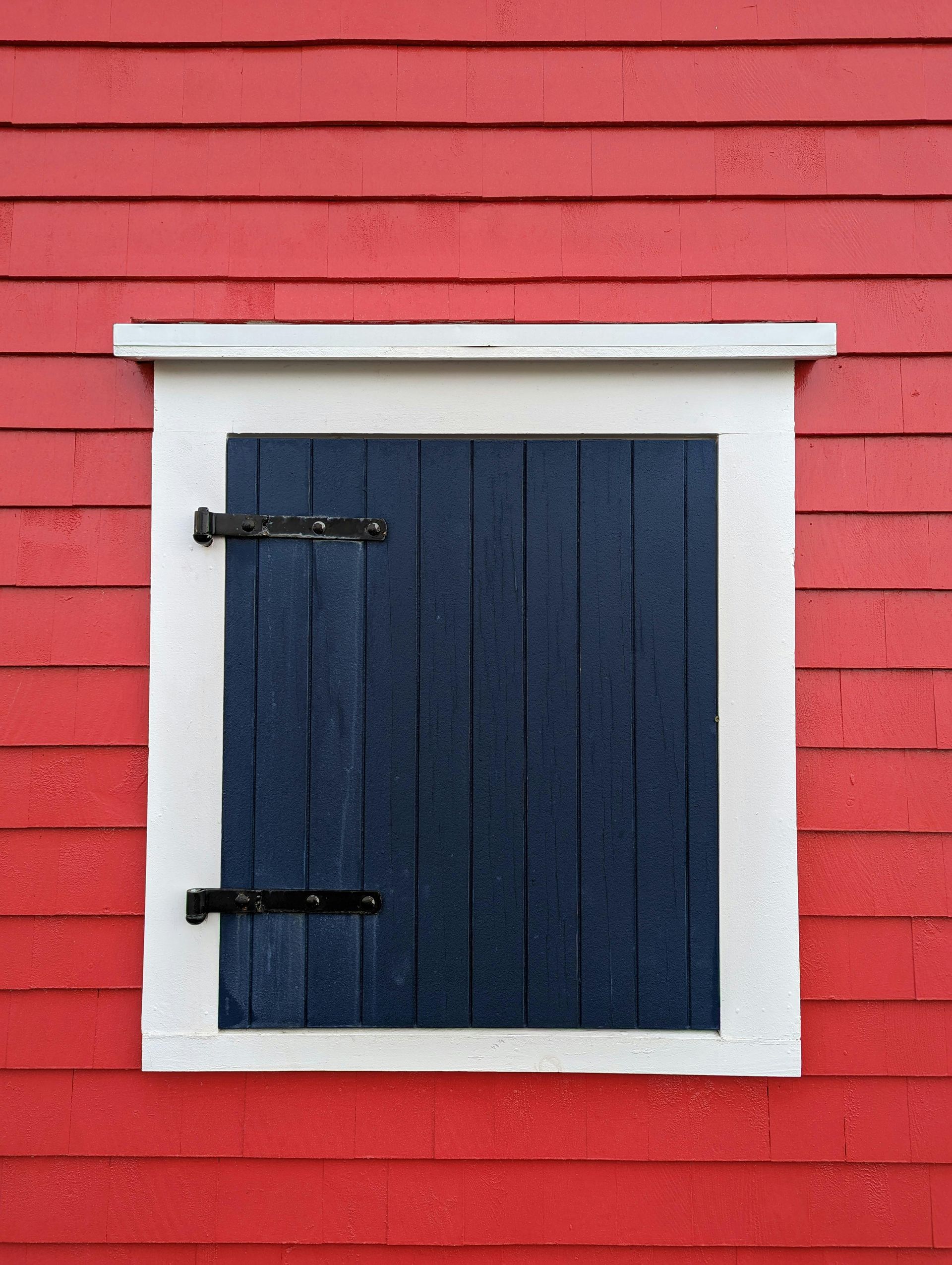 A door with blue shutters on a red wall