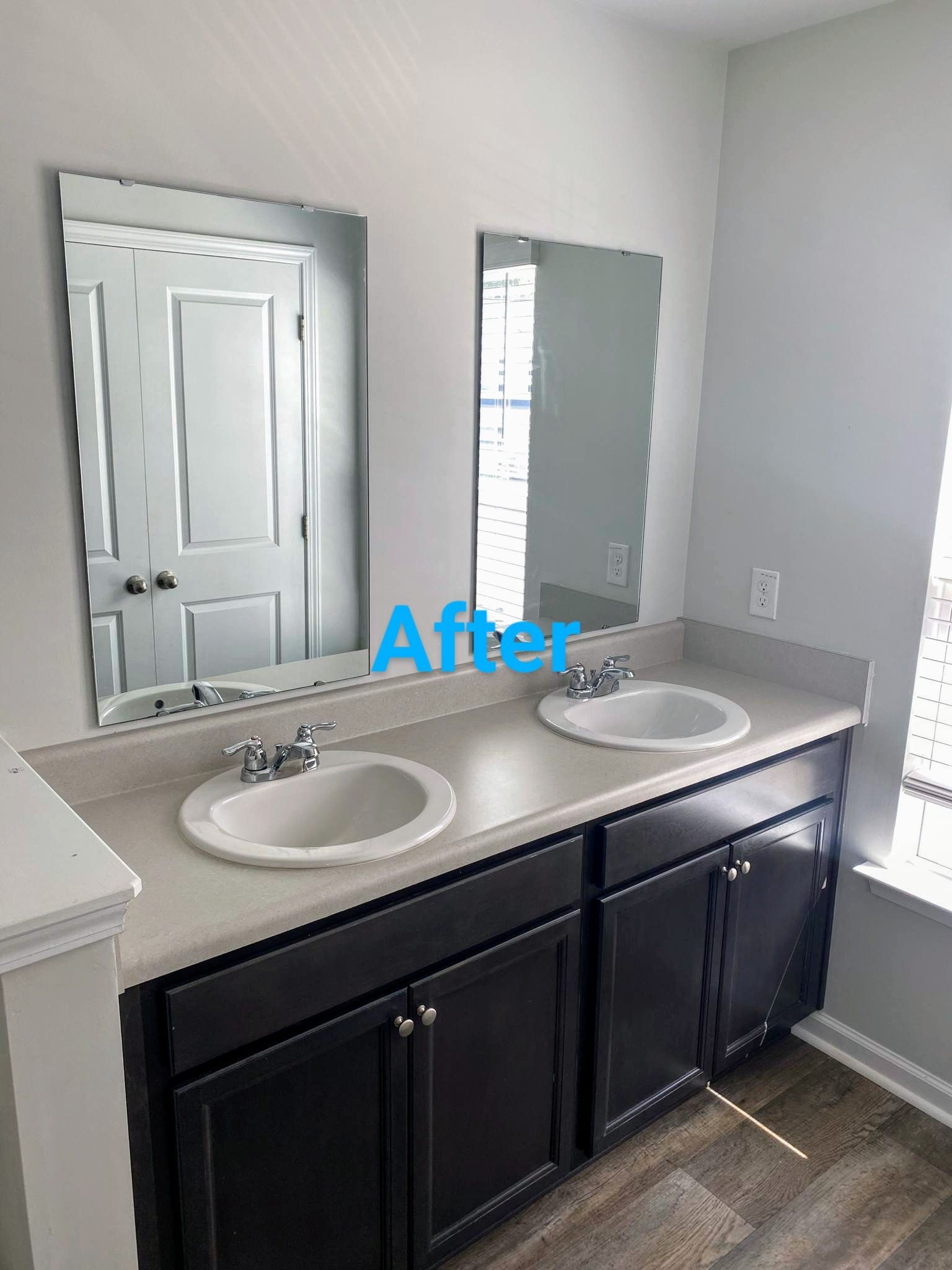 Bathroom with dark cabinets, light countertop, two sinks, two mirrors. 