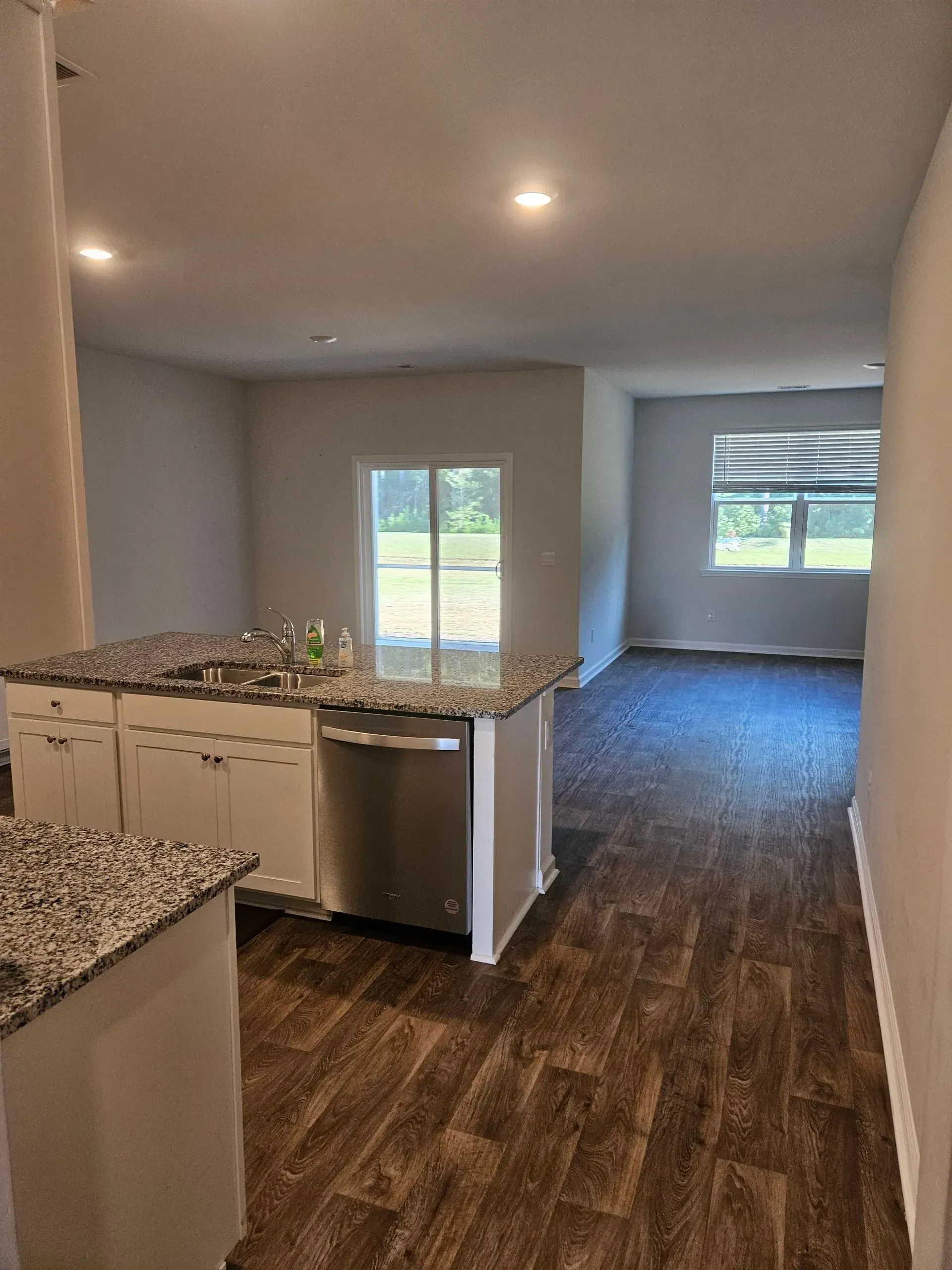 Kitchen with white cabinets, granite countertops, stainless steel appliances, and dark wood flooring.