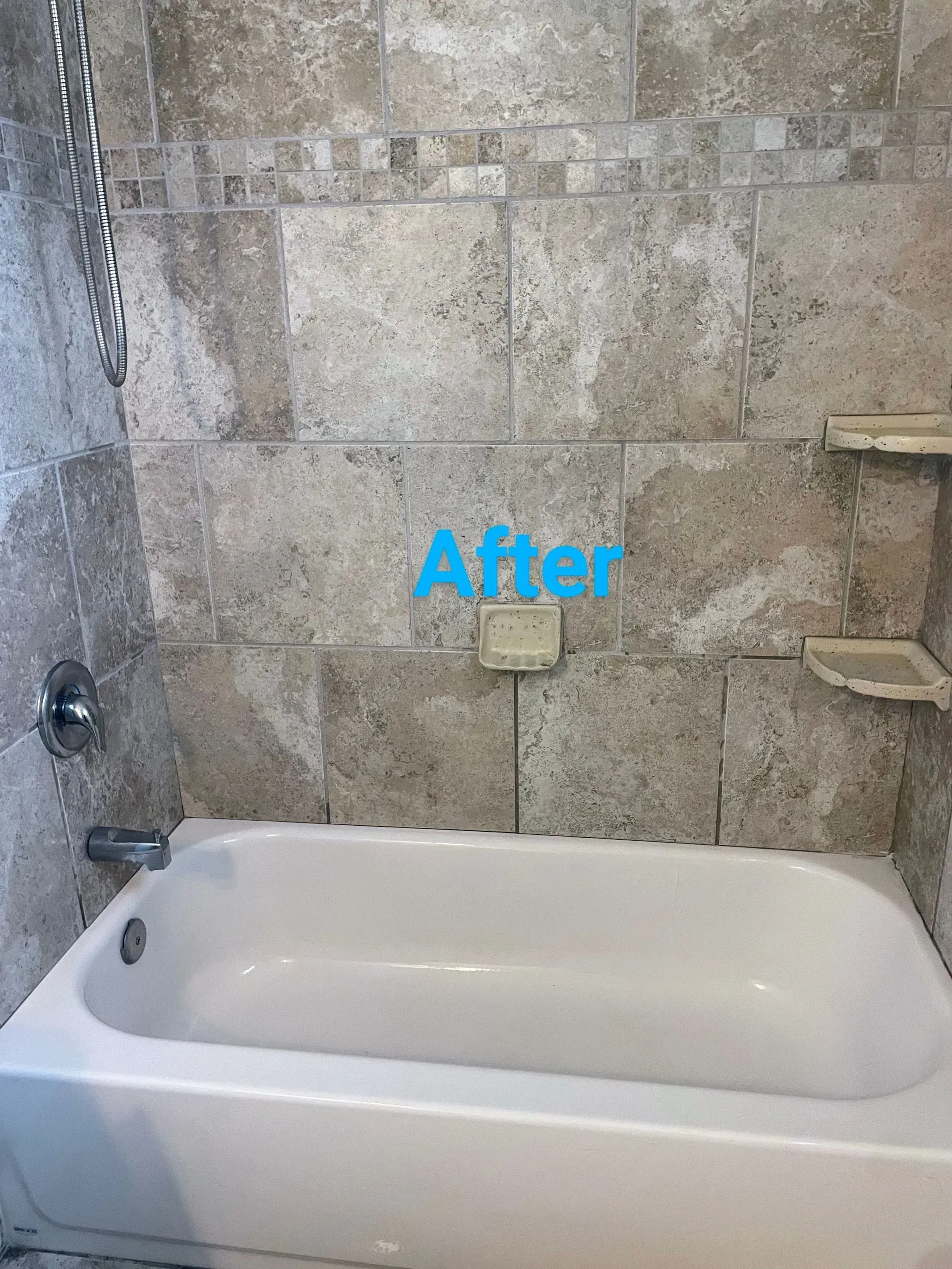 A clean bathroom tub with light tan tile wall and soap holder. 