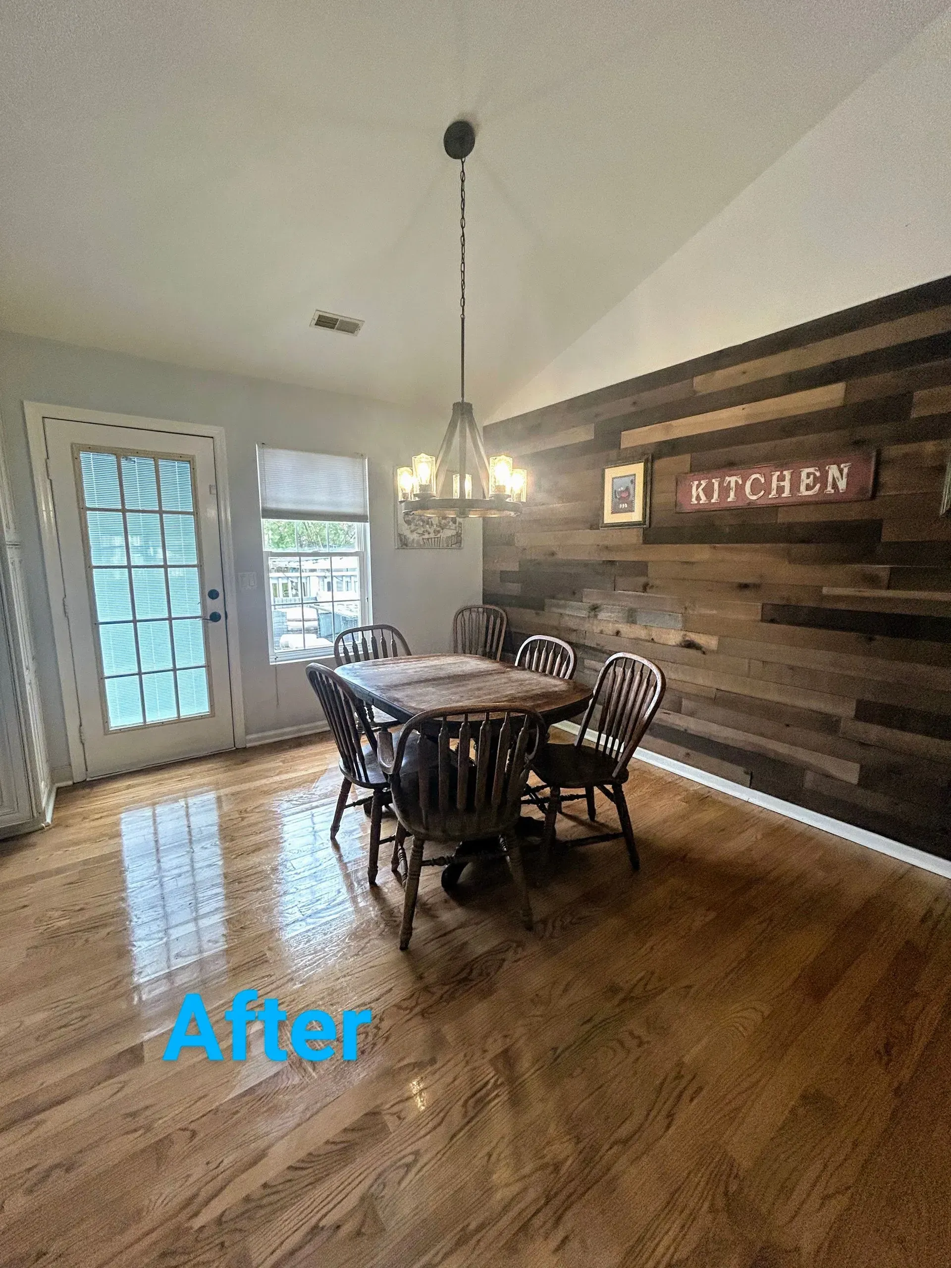 Dining room with wood plank wall, table, chairs, and hanging light fixture. 